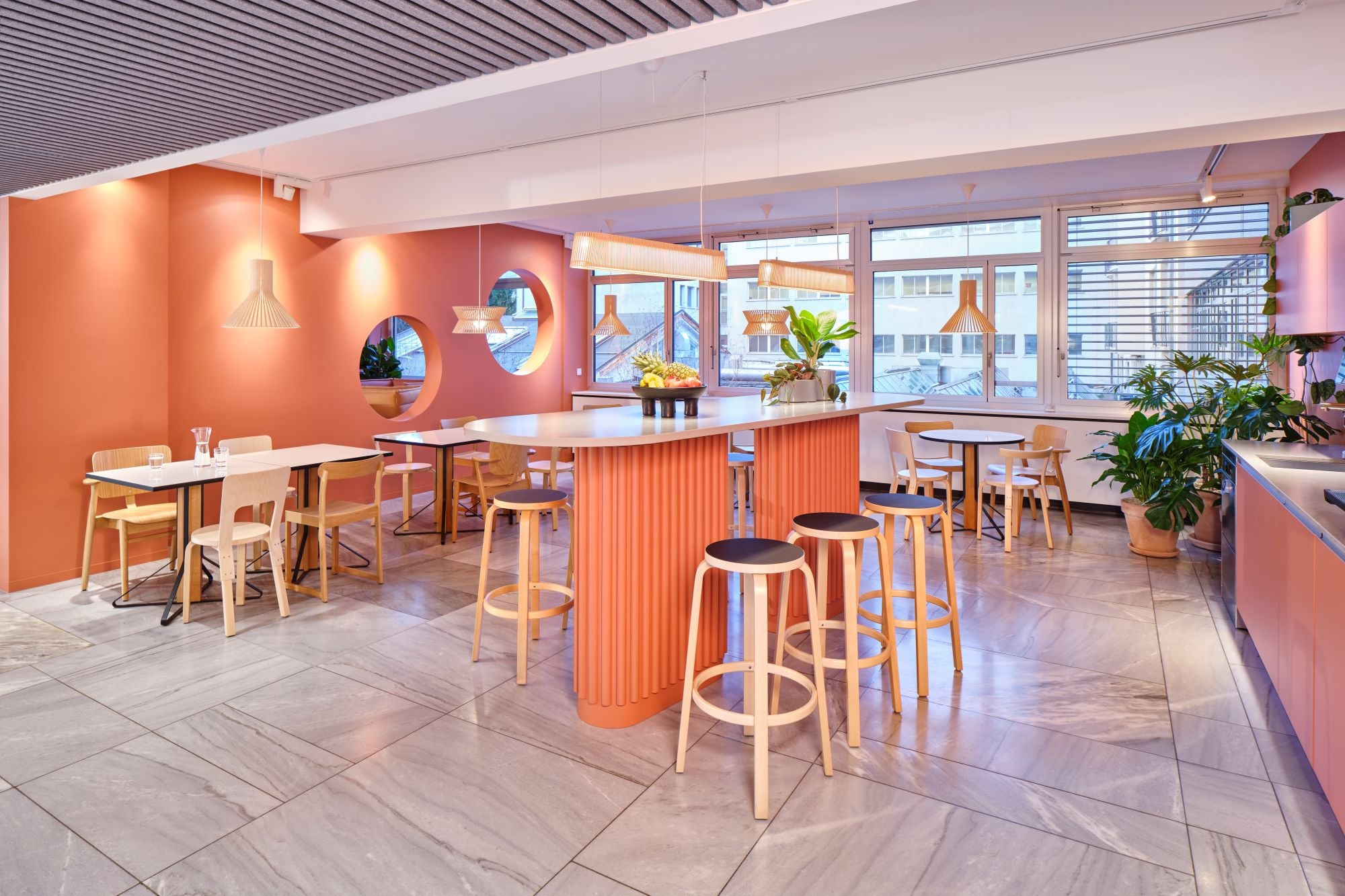 Modern cafe interior with orange walls, wooden furniture, and large windows.