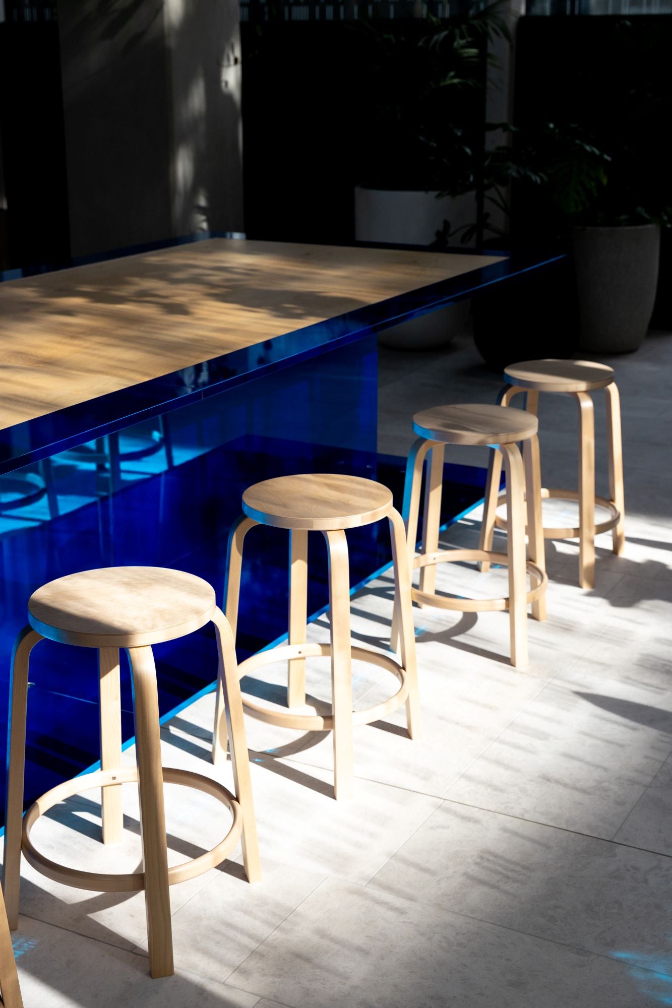 Wooden stools in front of a blue counter with a wooden top.