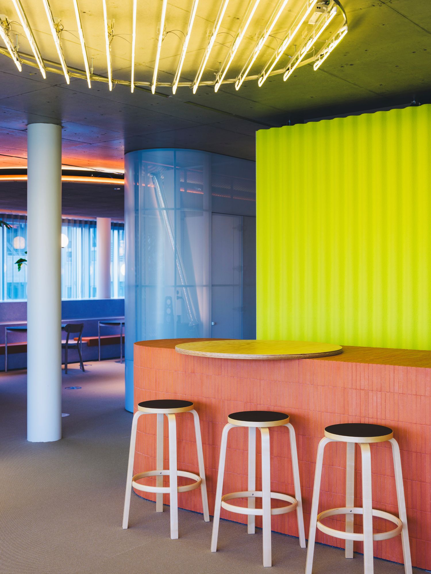 Modern interior with colorful walls, stools, and a unique ceiling design.