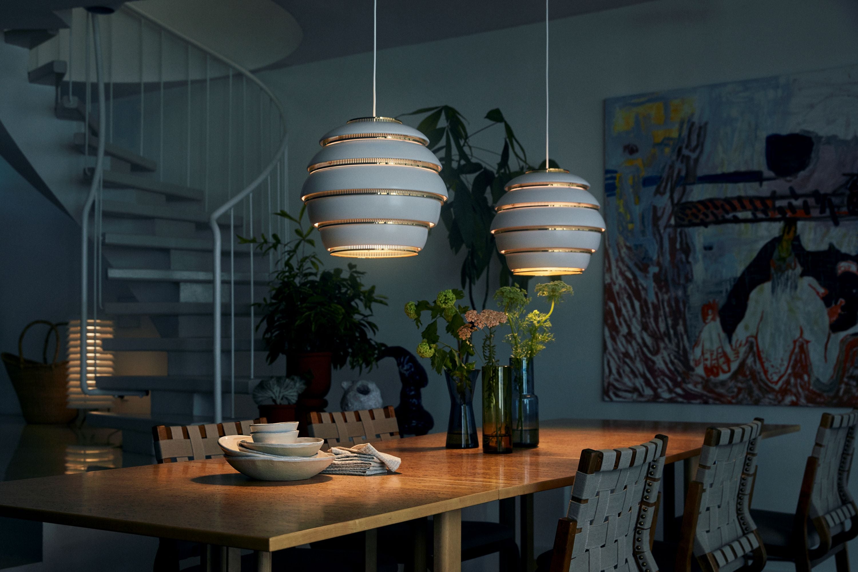 Dining room with wooden table, chairs, and pendant lights in a dimly lit setting.
