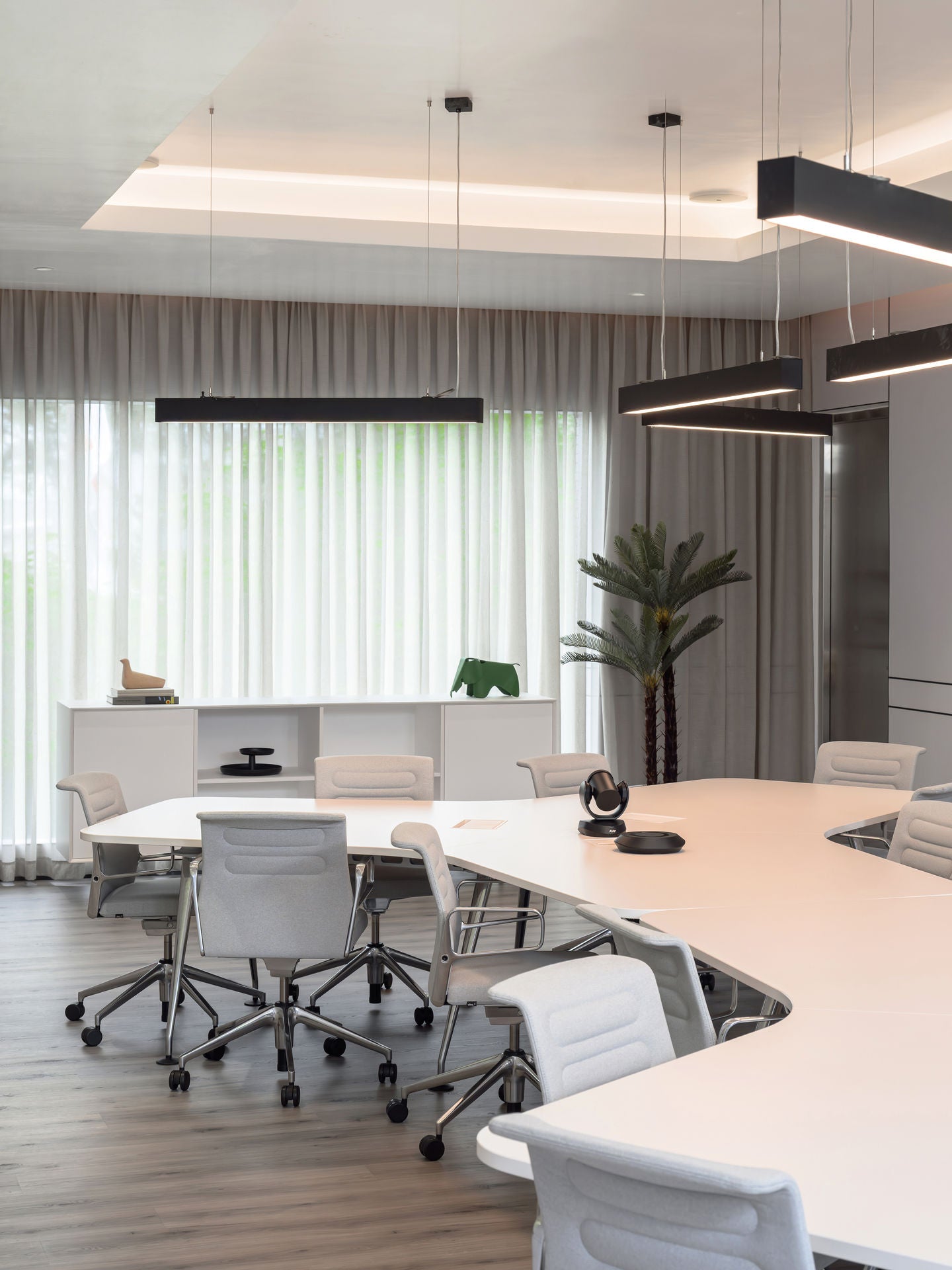 Modern office conference room with white furniture and large windows.