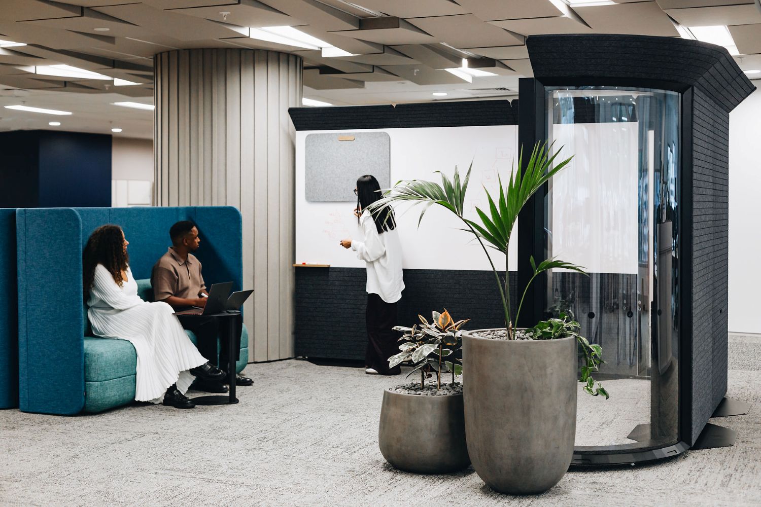 Modern office space with people working and a plant in the foreground