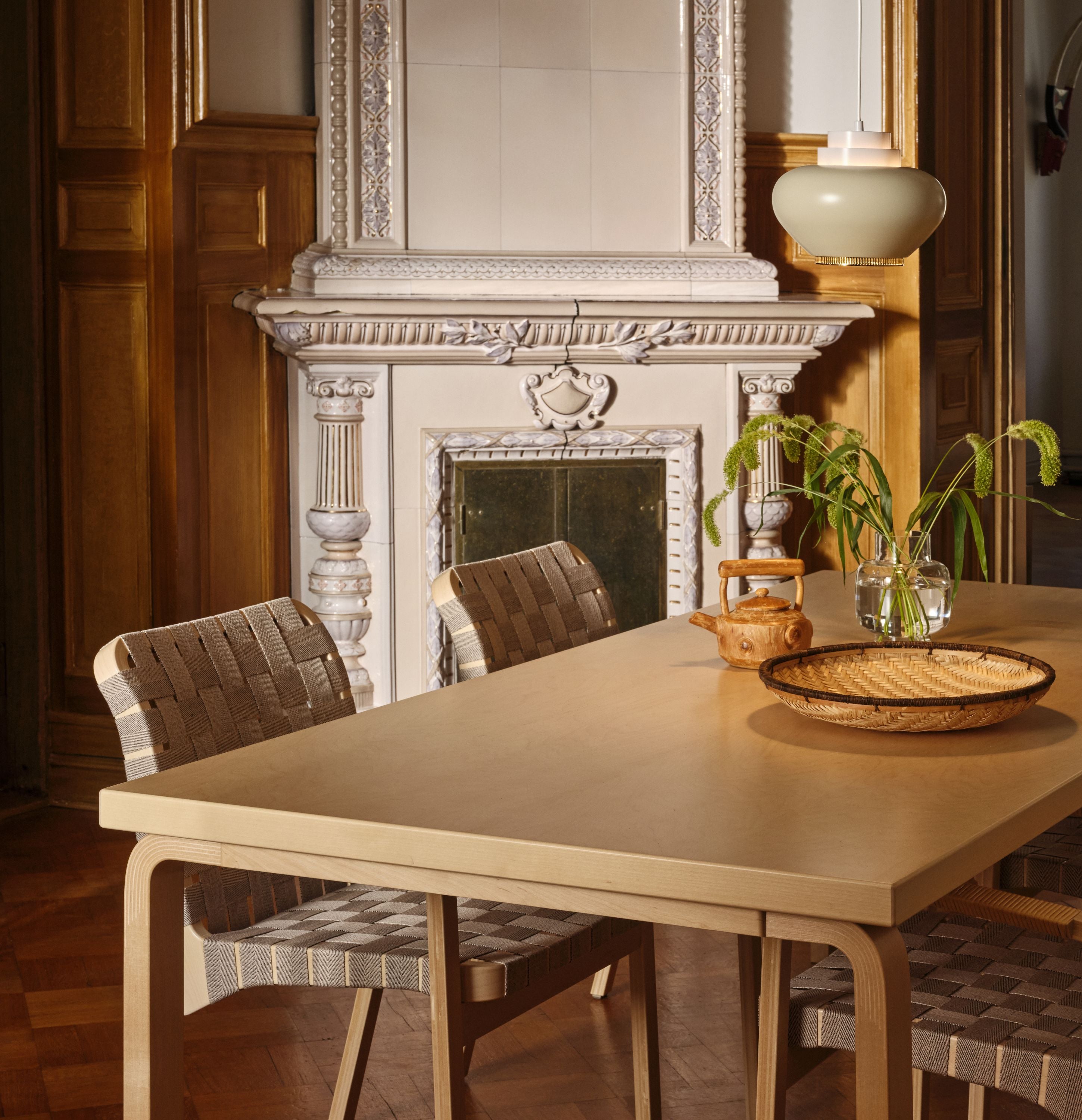 Dining area with a beige table and chairs in front of a fireplace.