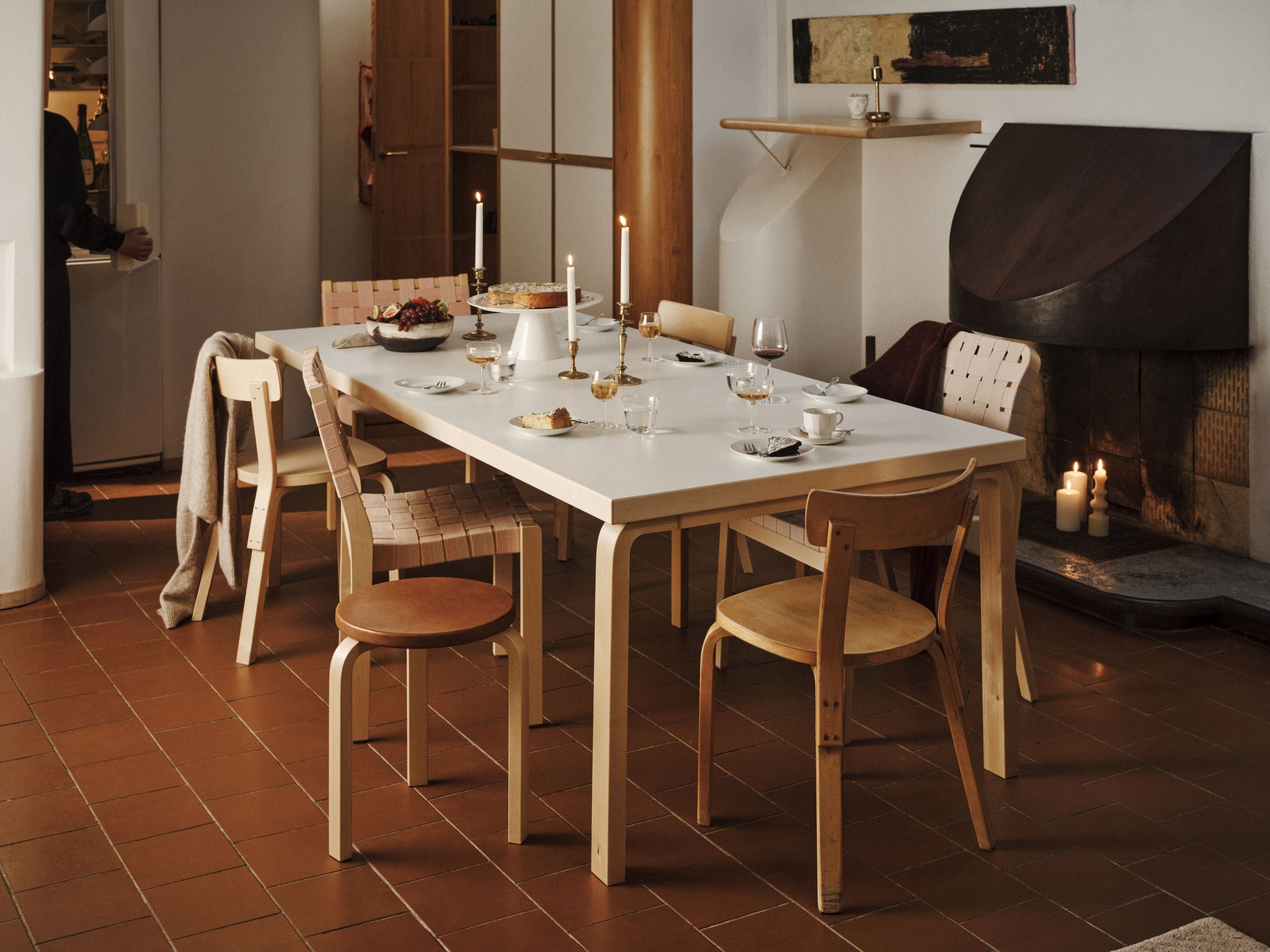 Dining area with a table set for a meal, chairs, and a fireplace in the background.