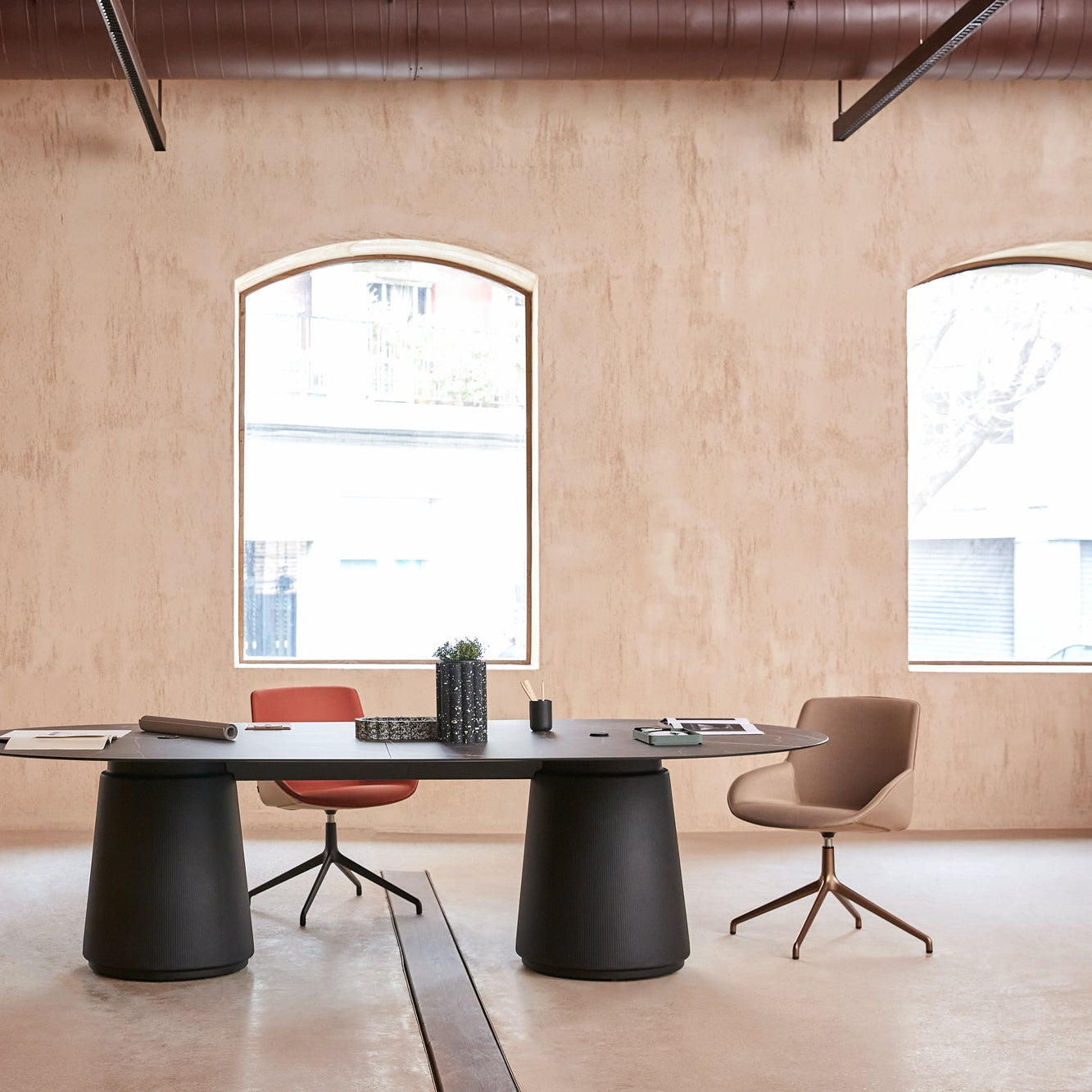 Modern office setup with a round black table and chairs in a room with large windows.