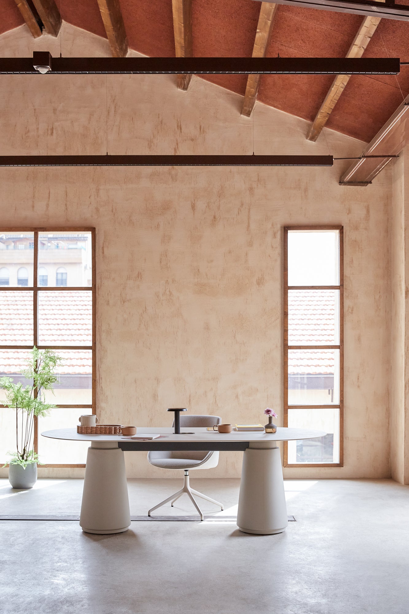 Modern dining area with a white table and chairs in a room with wooden beams and large windows.