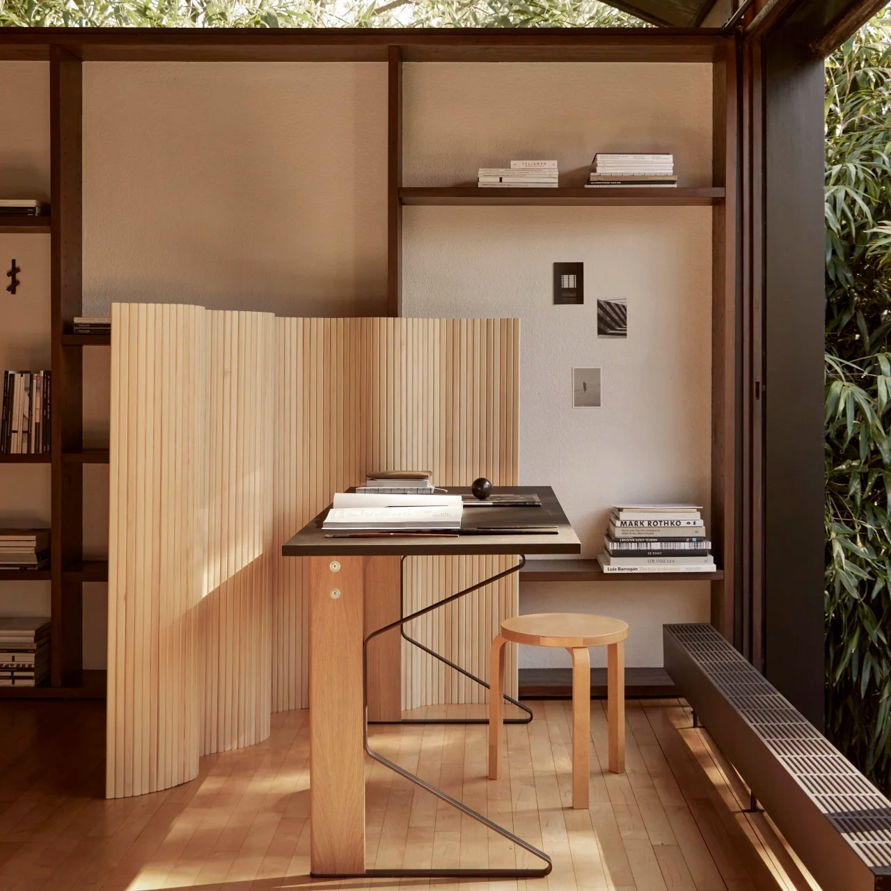 Modern home office with wooden desk, shelves, and a view of trees
