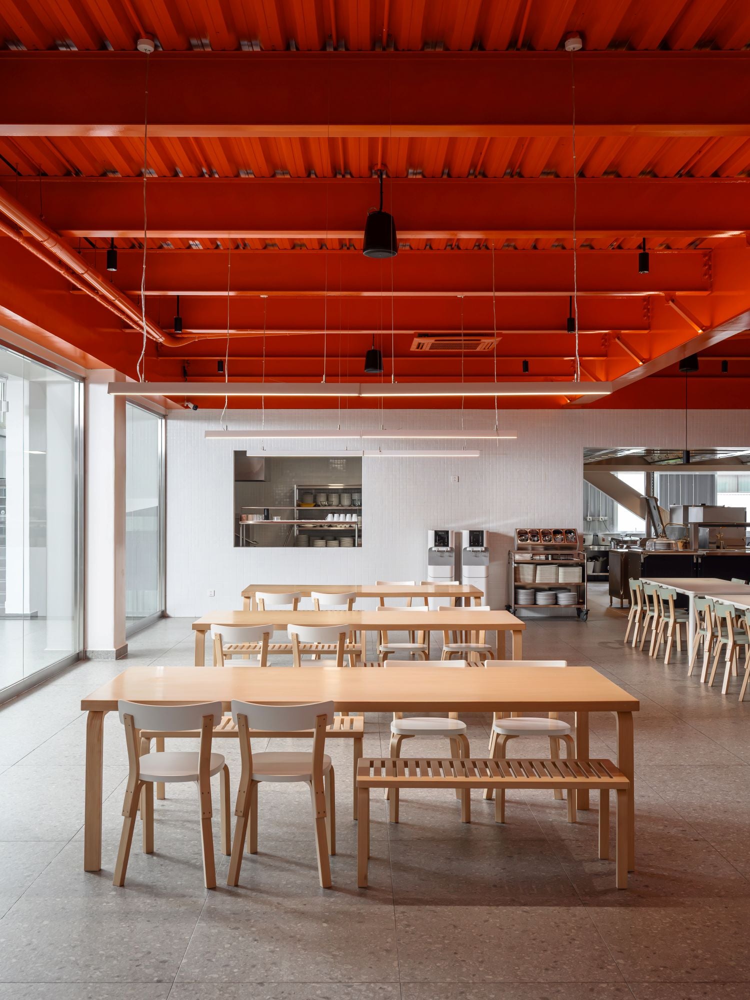 Modern interior with wooden tables and chairs against a bright orange ceiling.