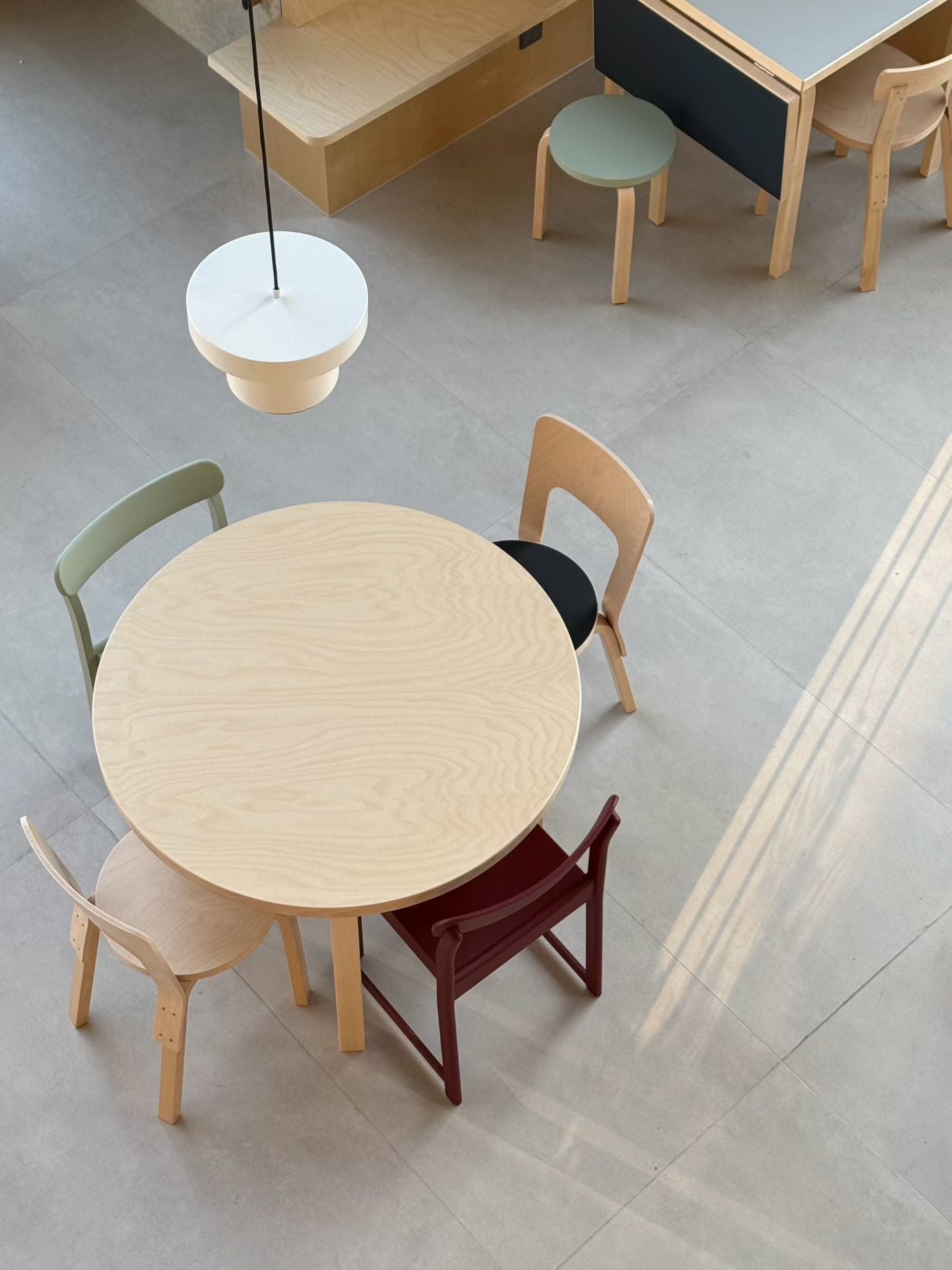 Round wooden table with colorful chairs in a minimalistic setting