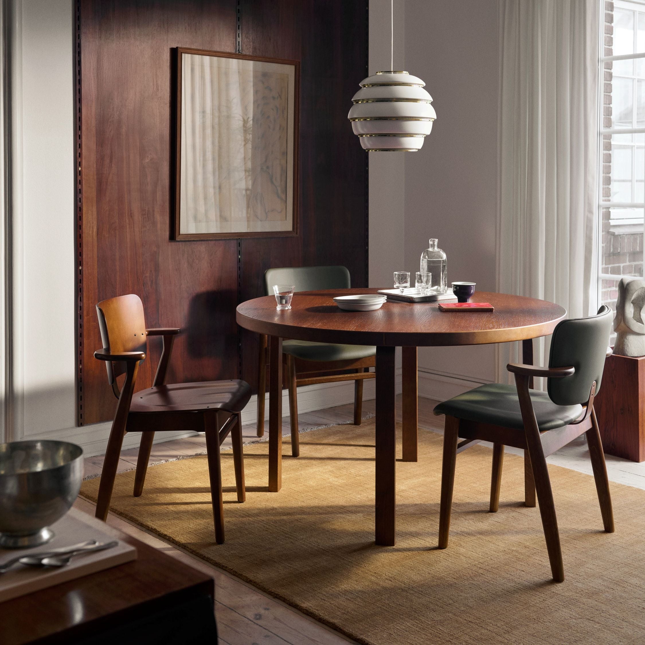 Modern dining room with wooden table and chairs, pendant light, and abstract painting.