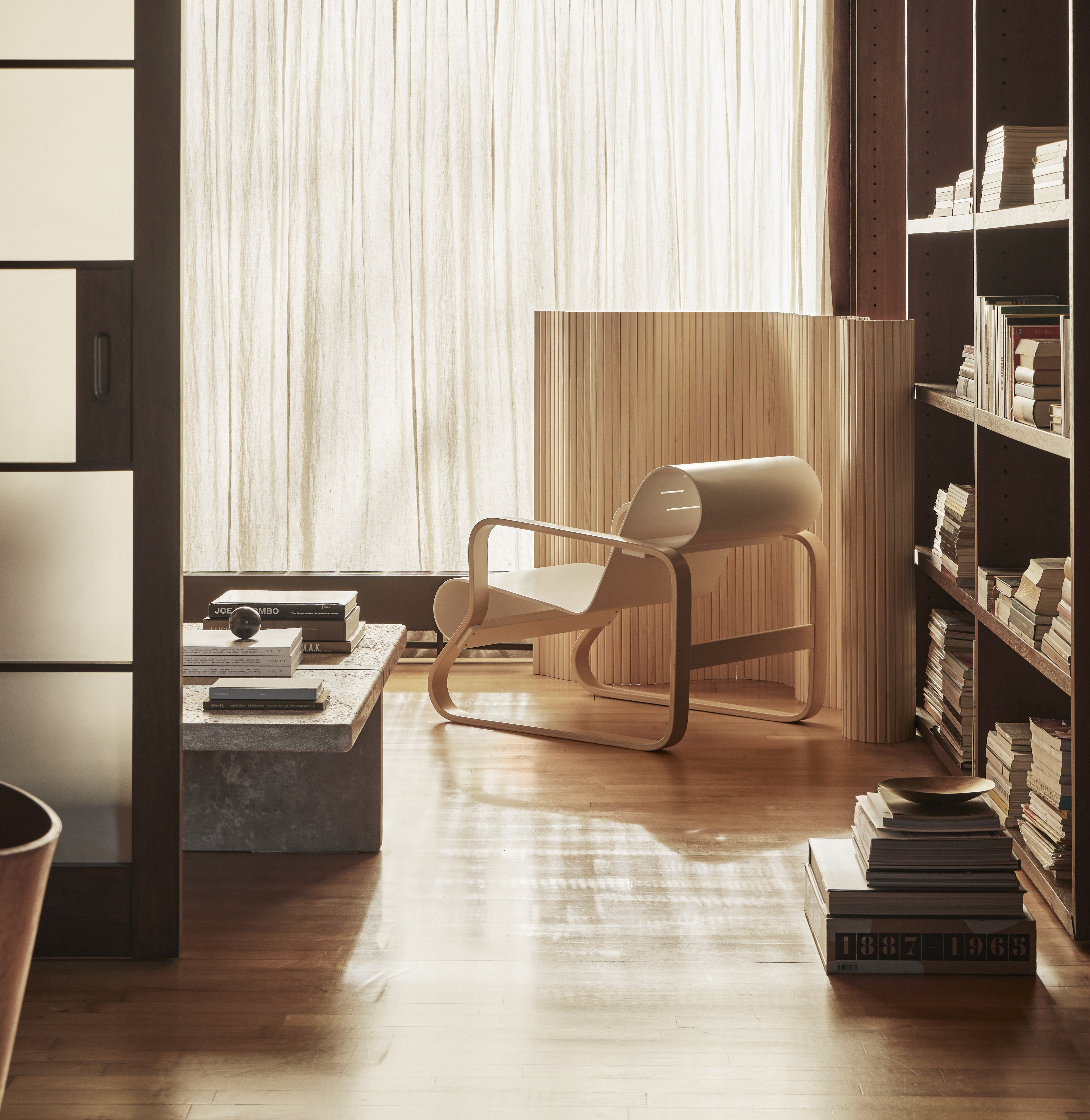 Modern living room with a chair, coffee table, and bookshelf.