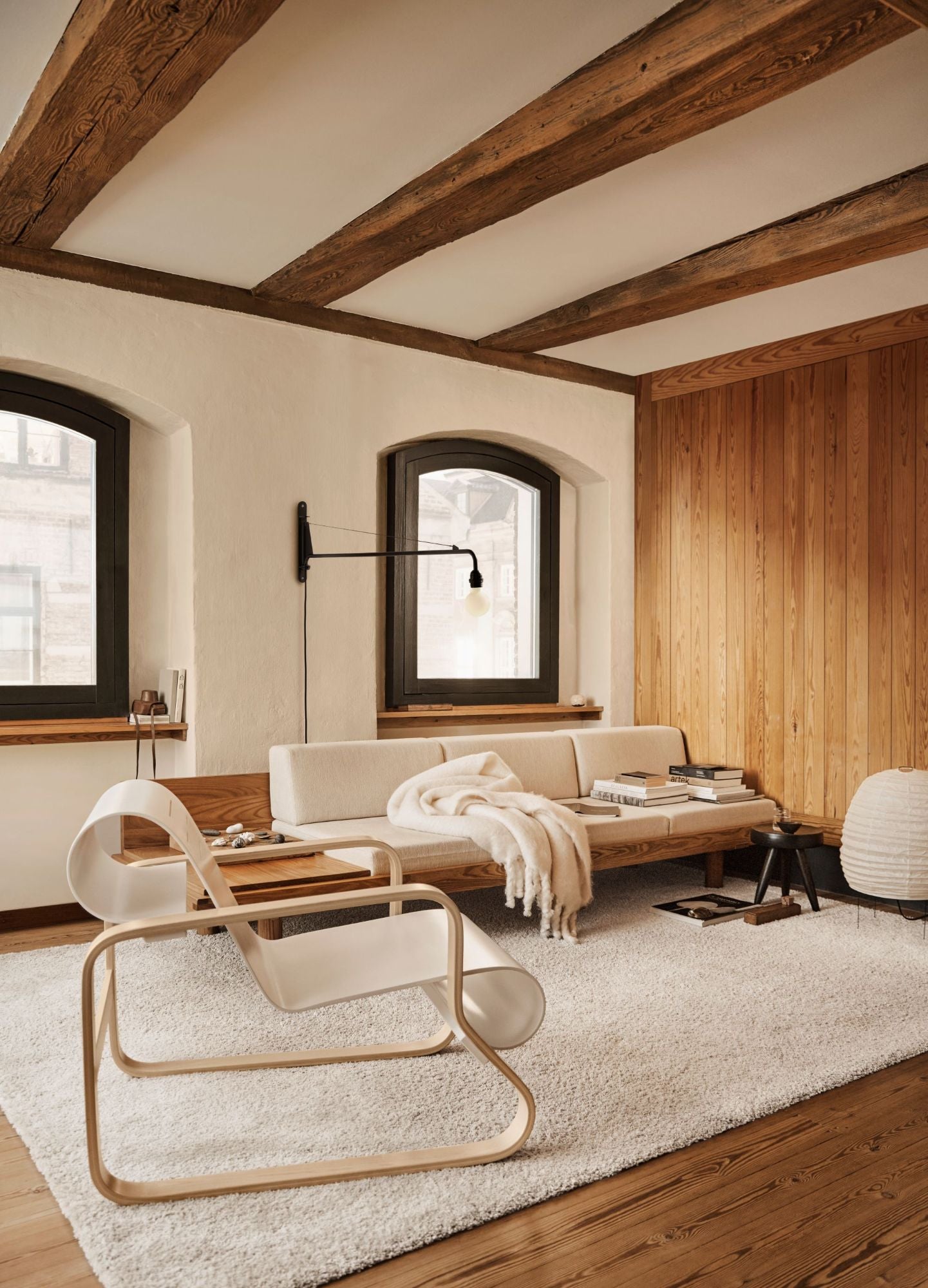 Modern living room with wooden beams, a white sofa, and a chair.