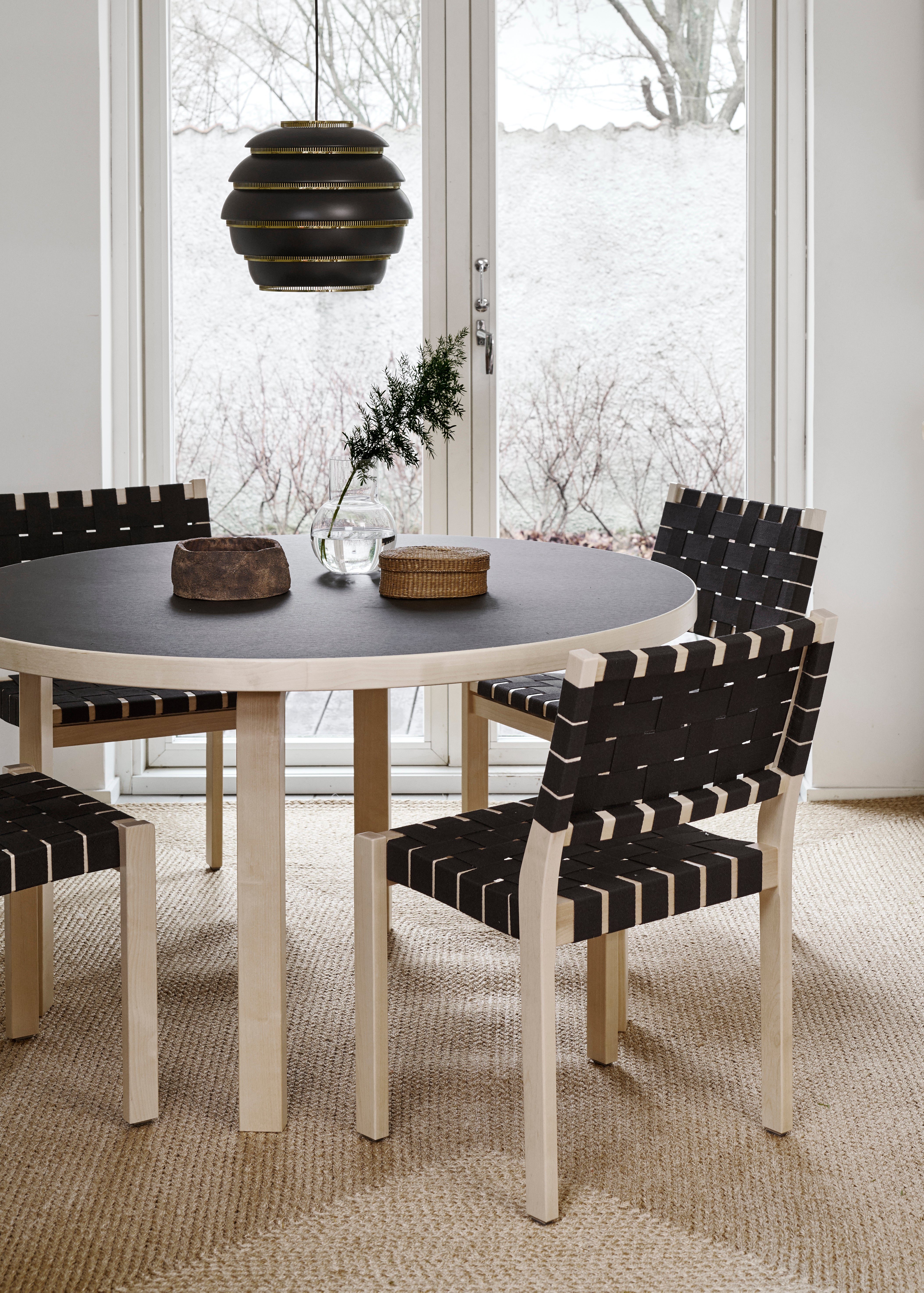 Dining room with round table and black and white chairs near a large window.
