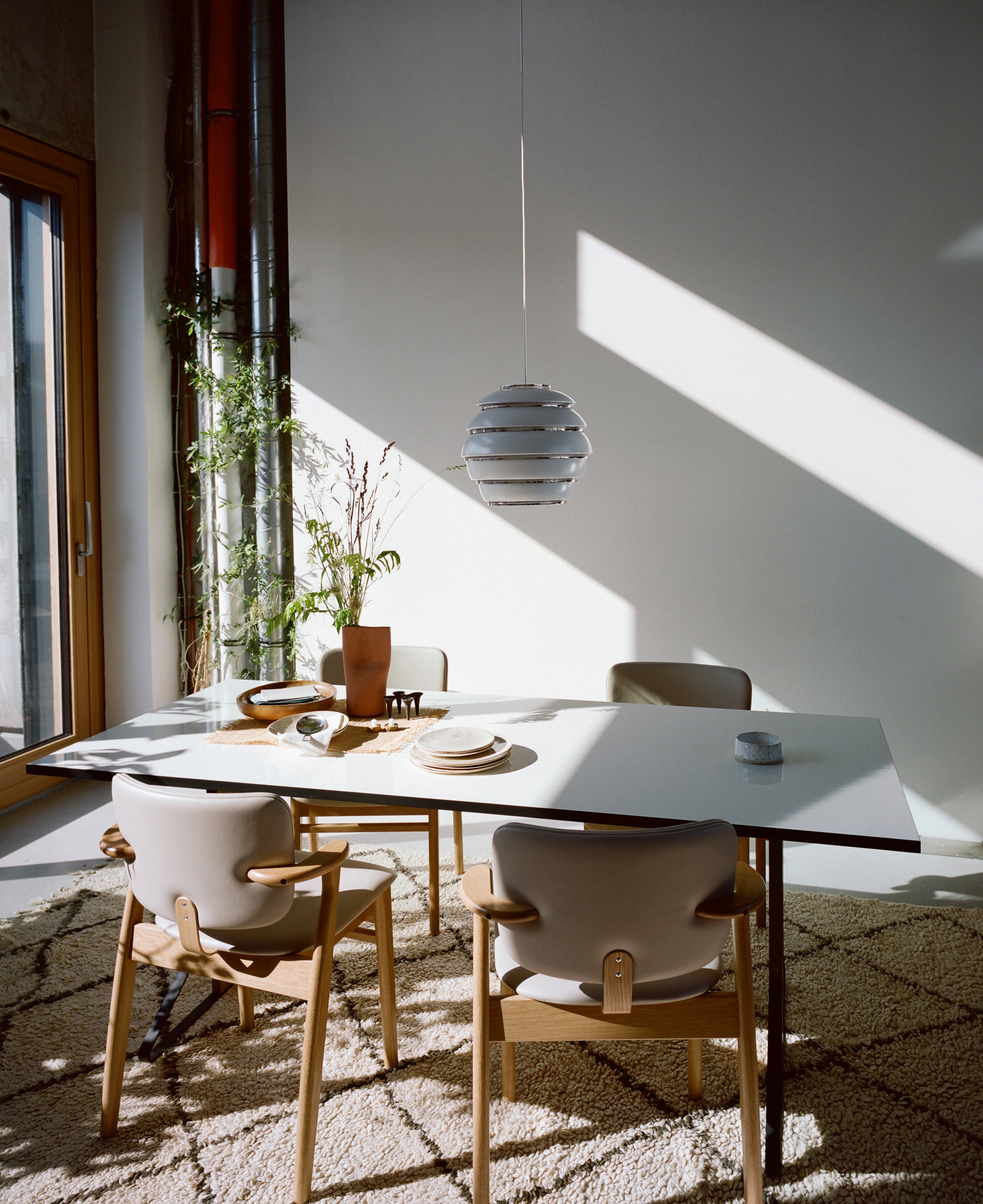 Dining area with a table and chairs in a well-lit room with sunlight streaming through a window.