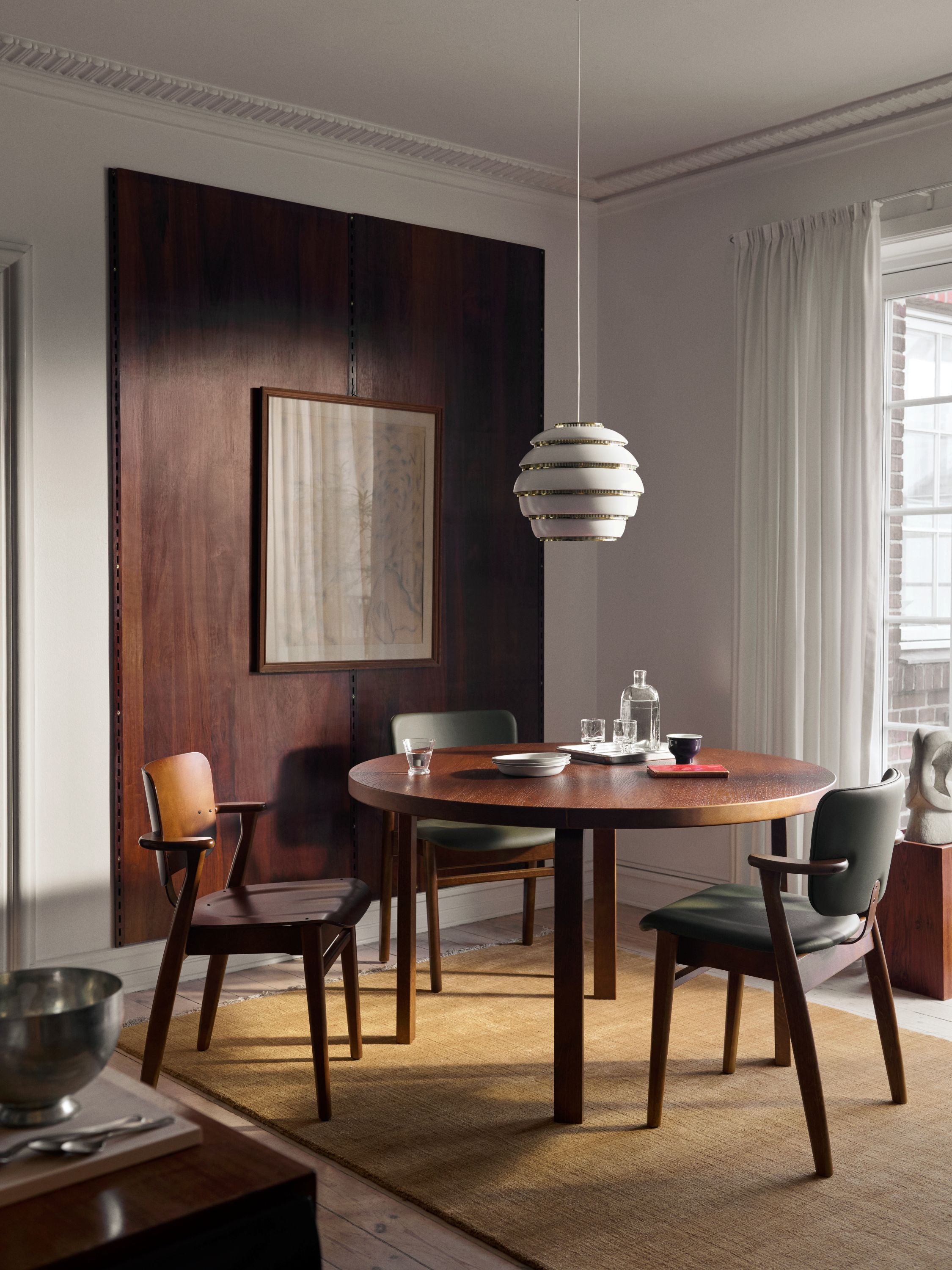 Modern dining room with wooden table and chairs, pendant light, and abstract painting.