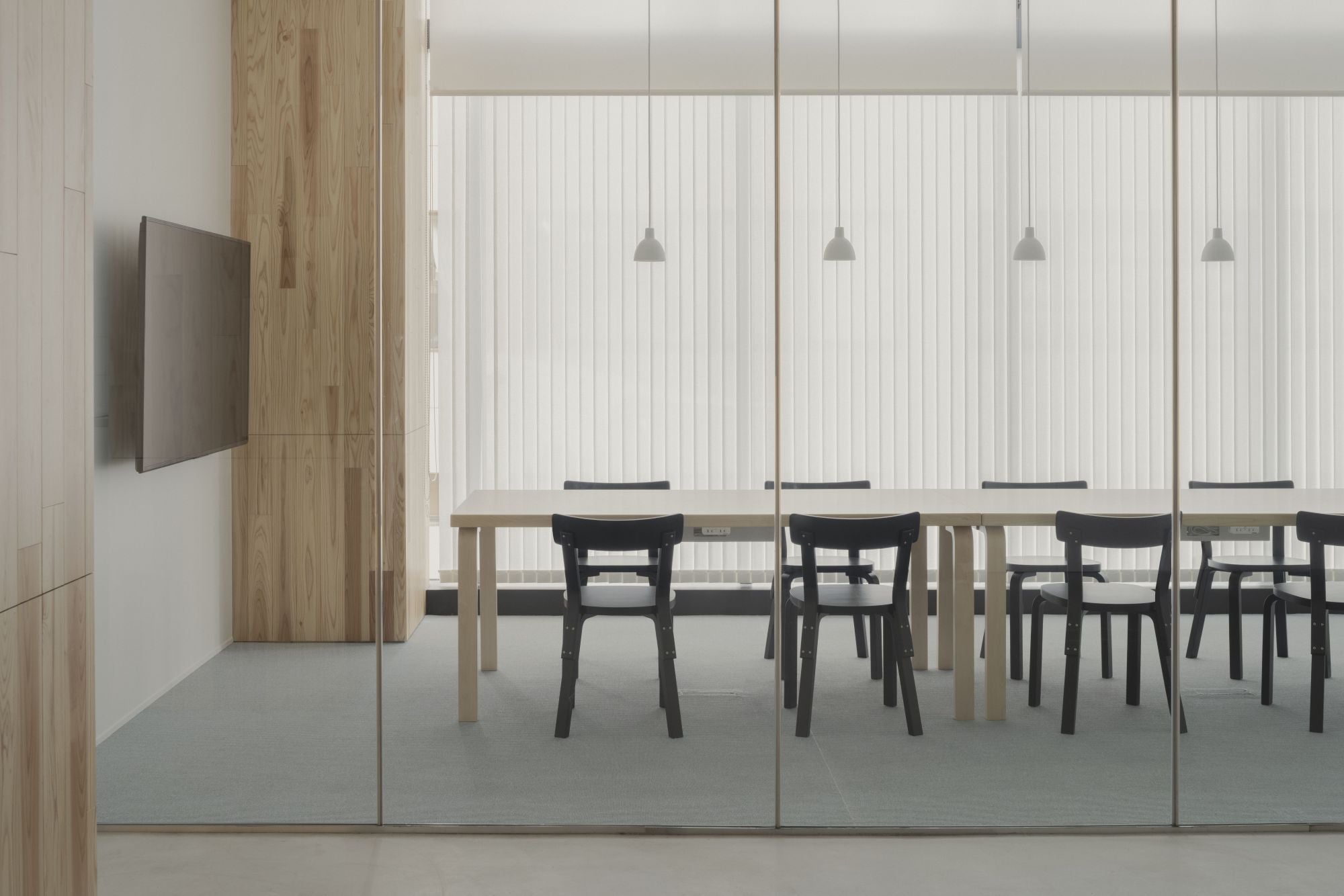 Modern office conference room with glass walls, wooden paneling, and a table with chairs.