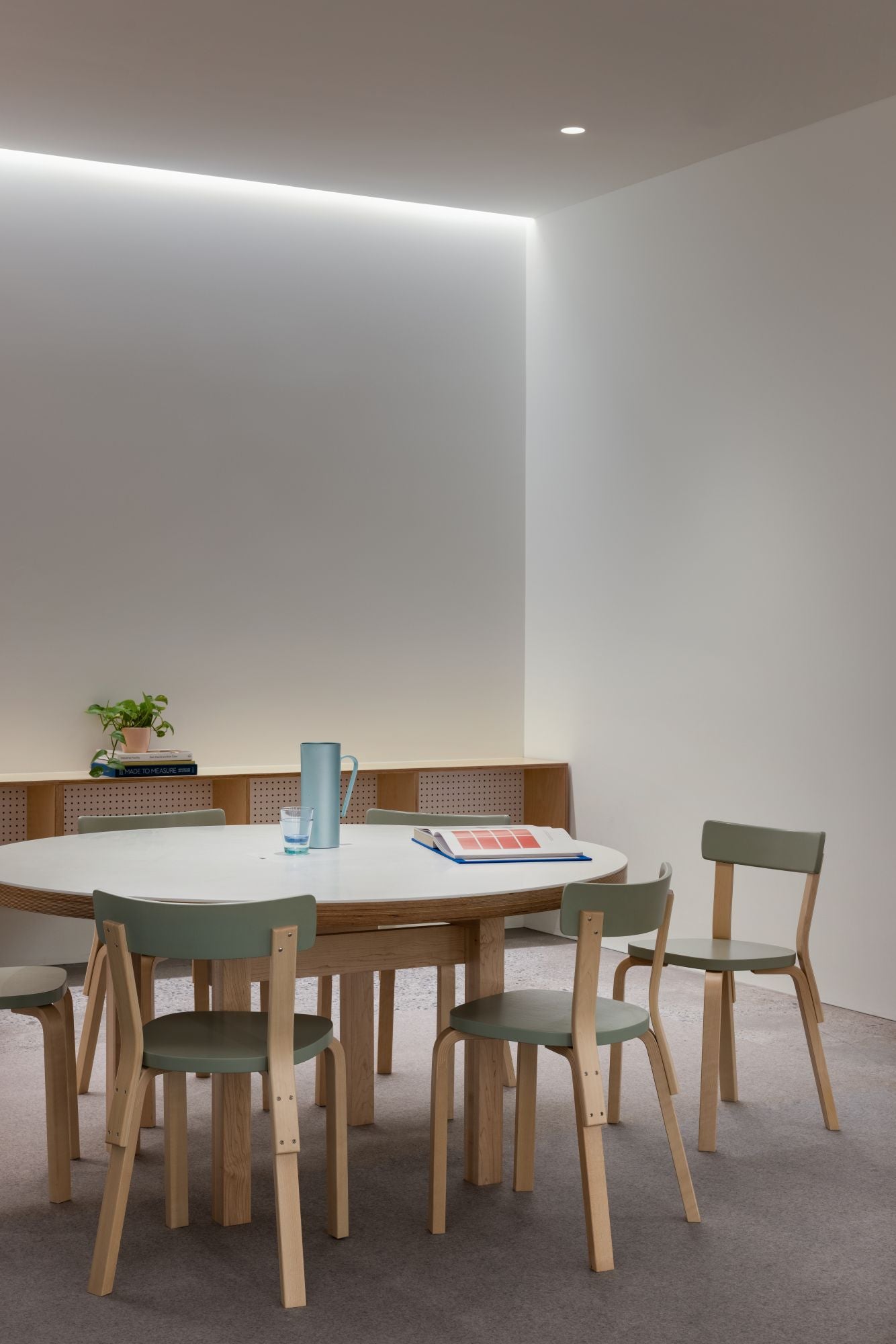 Round wooden dining table with chairs in a minimalistic room.