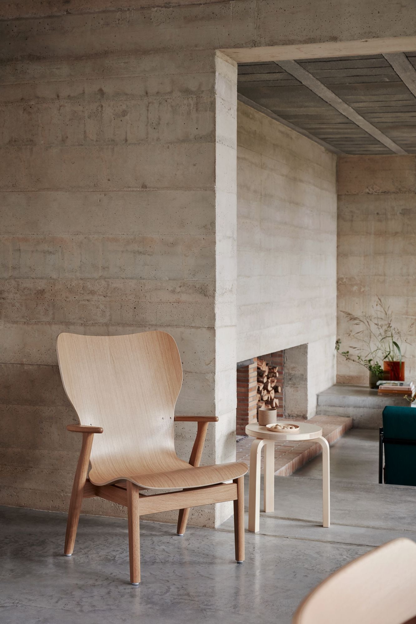 Wooden chair in a modern room with concrete walls and a fireplace.
