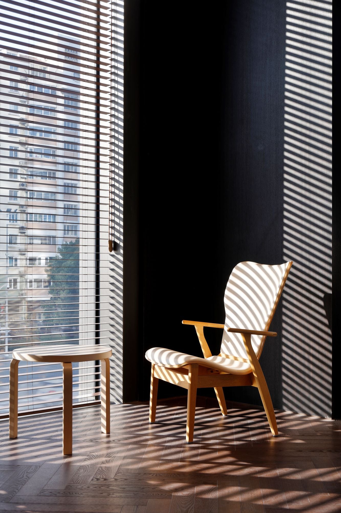 Wooden chair and small table in a room with sunlight filtering through blinds.