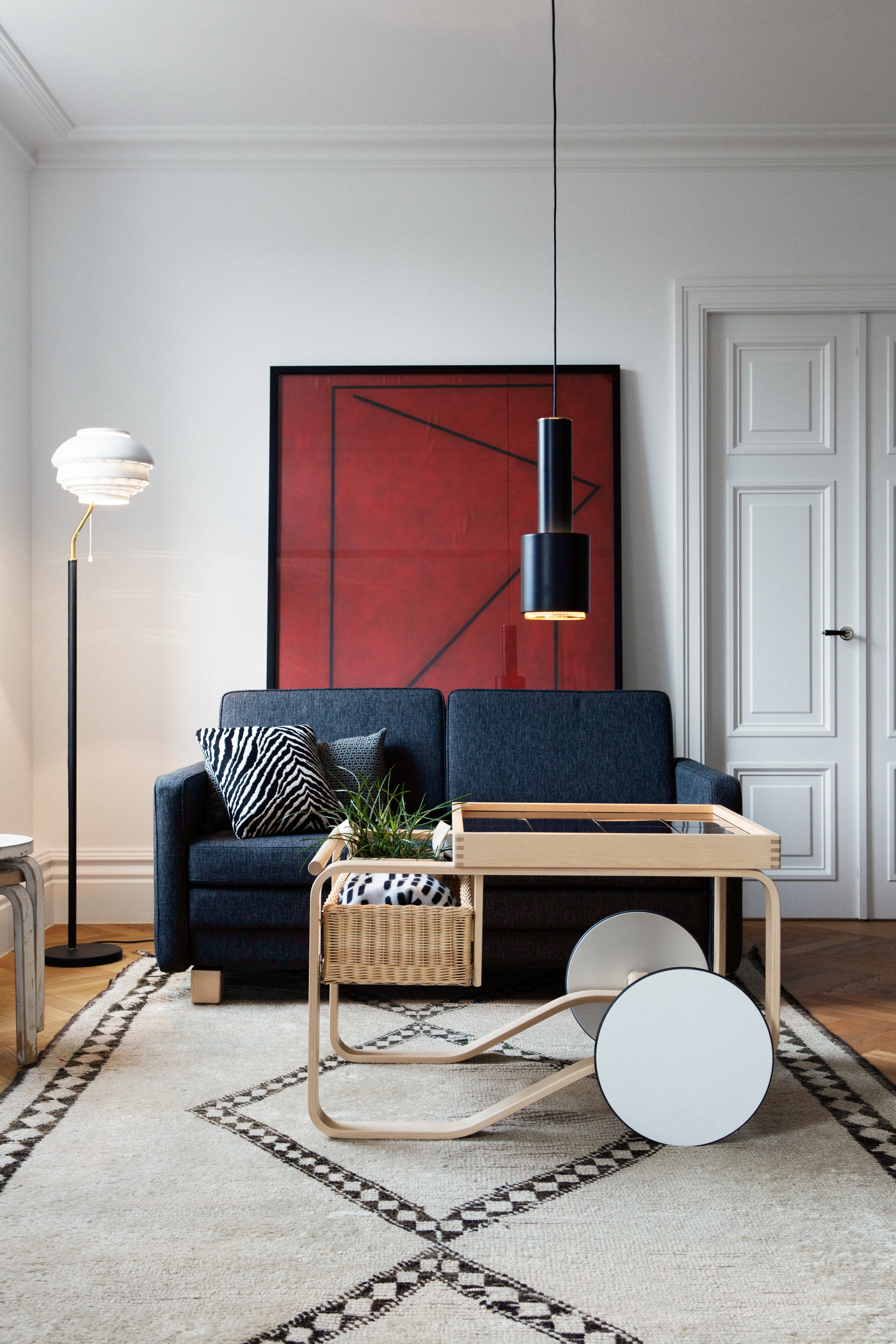 Modern living room with a blue sofa, wooden coffee table, and abstract art on the wall.