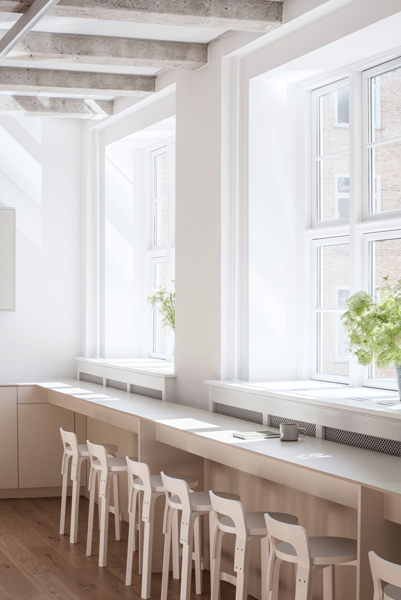 Modern kitchen with long counter, stools, and large windows.
