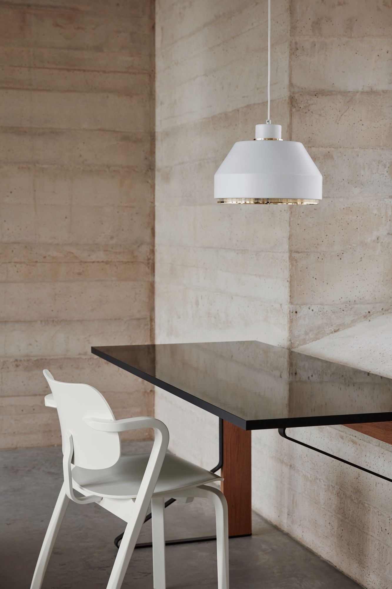 Modern dining area with a black table and white chair against a textured wall.