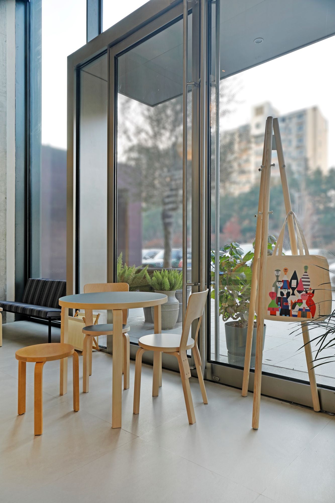 Modern interior with wooden furniture and an easel against a large window.