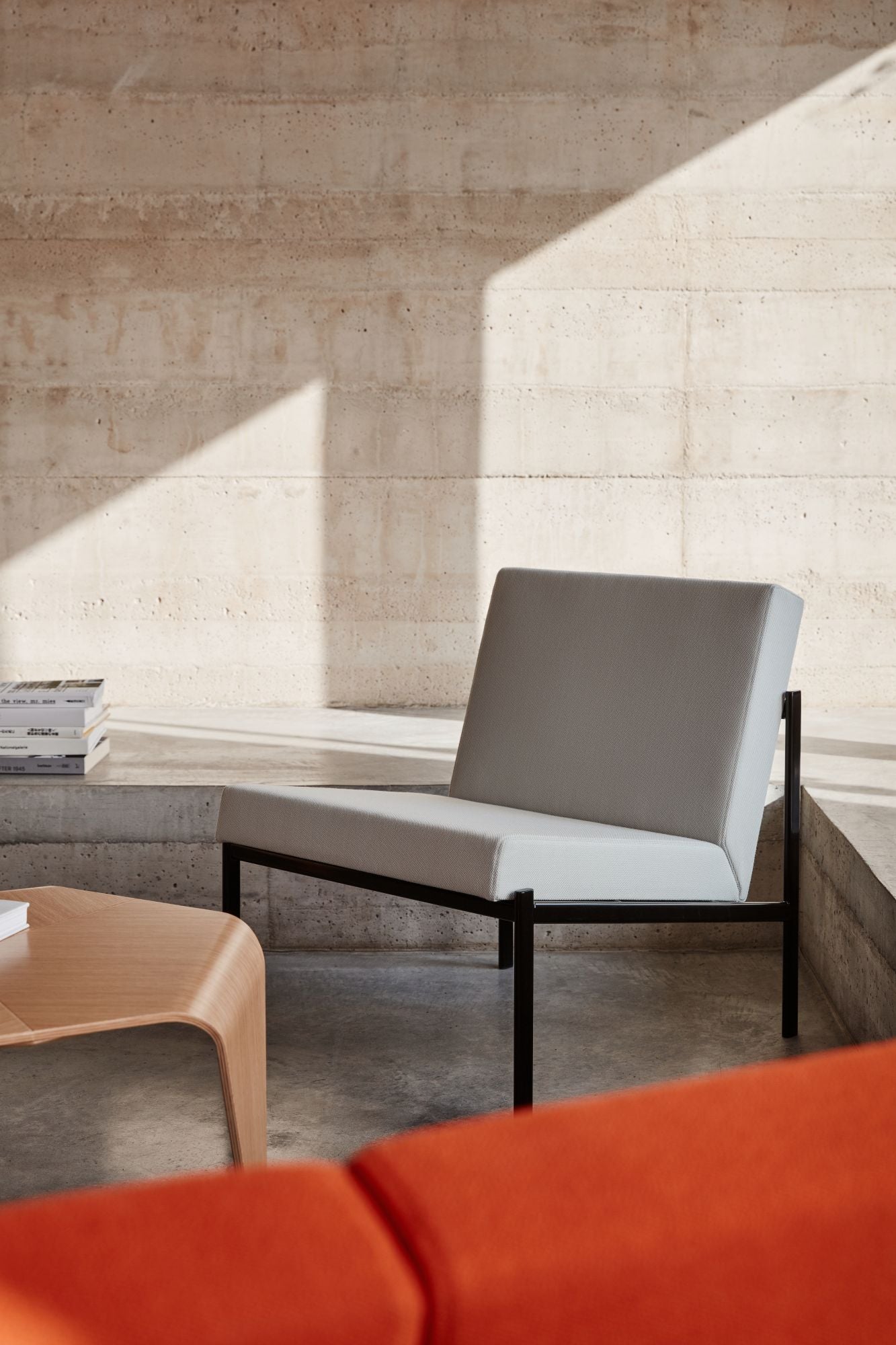 Modern chair with a neutral cushion in a minimalistic room with concrete walls.