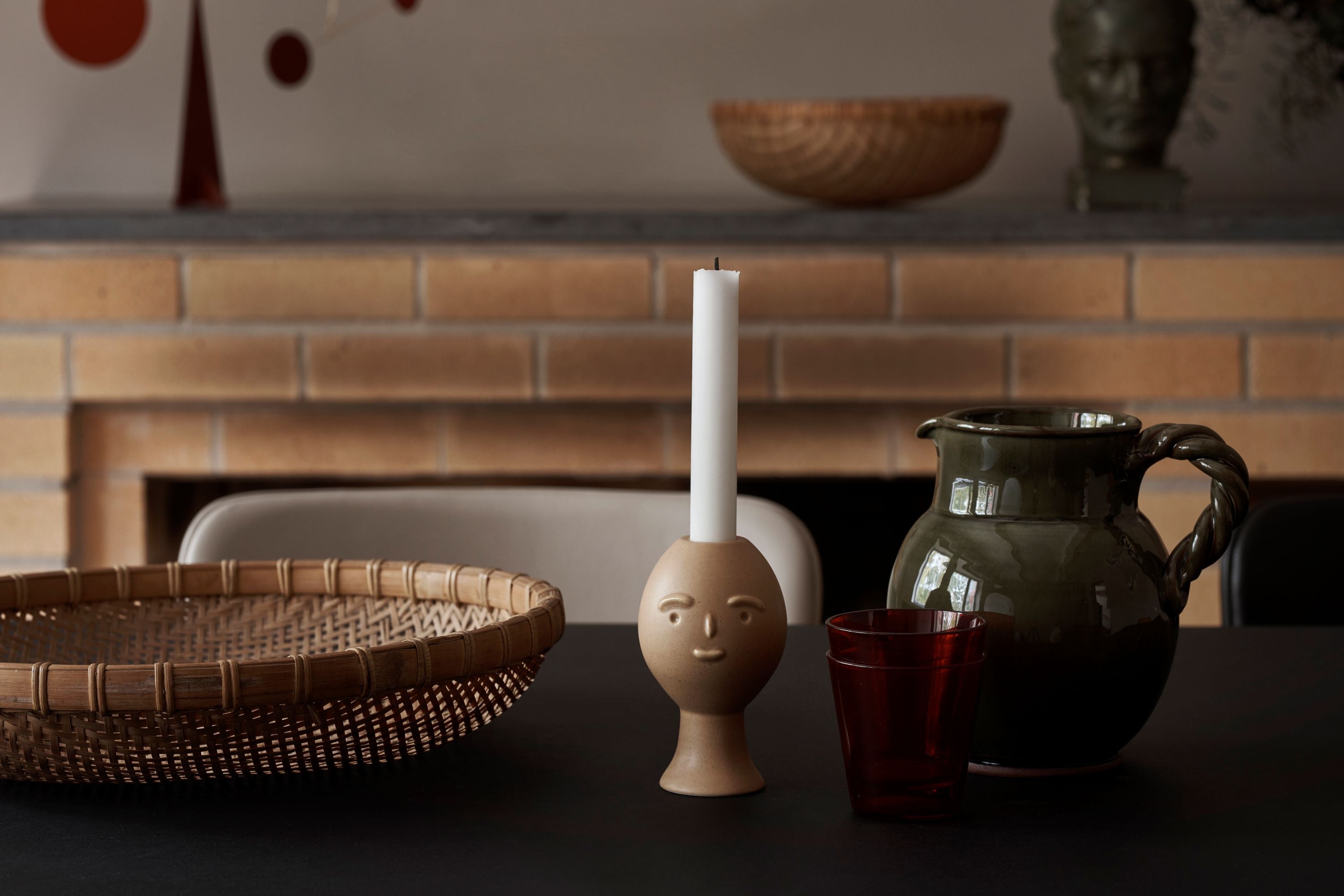 Decorative items including a basket, candle holder with a candle, and a pitcher on a table.