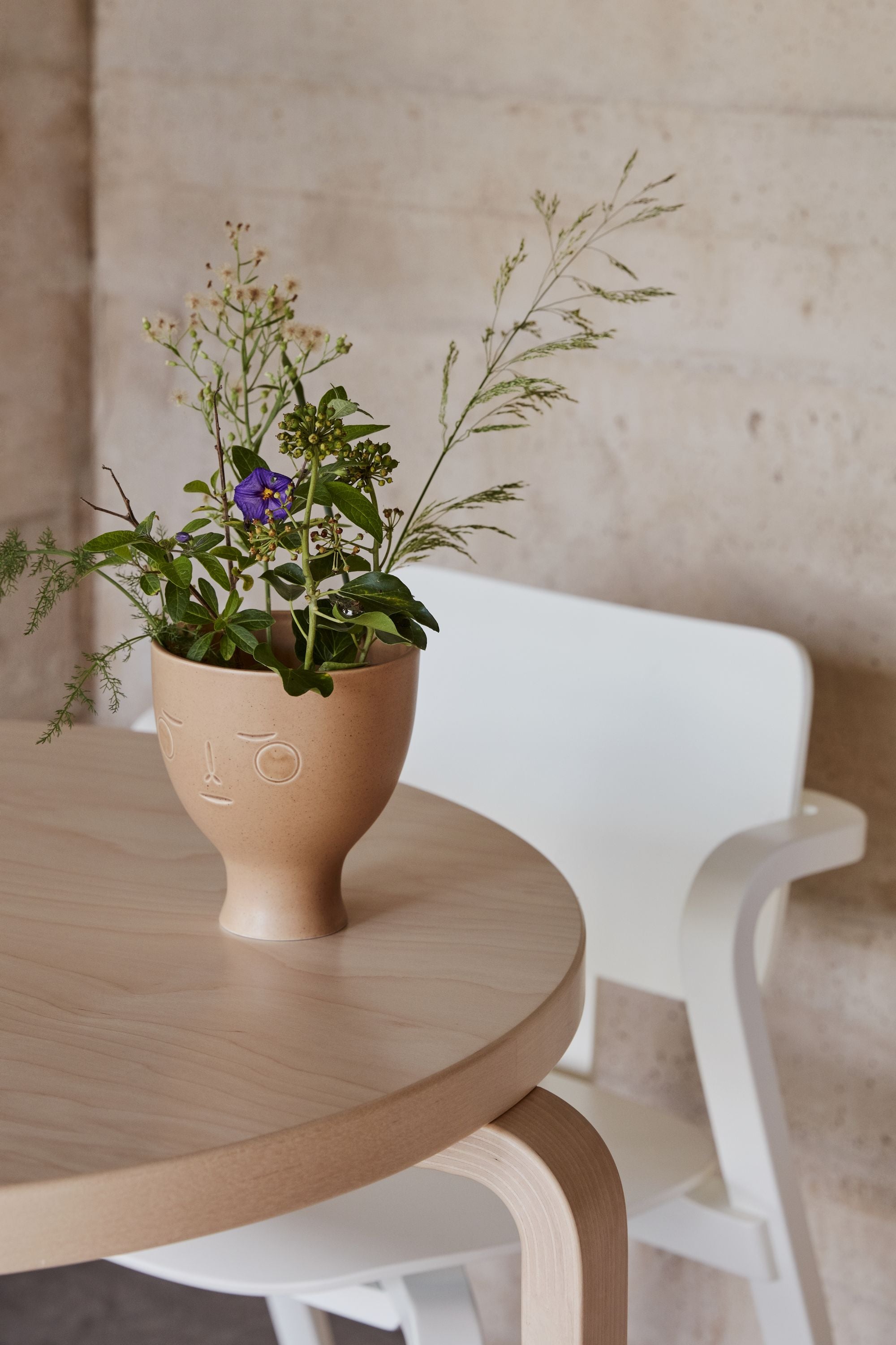 Vase with flowers on a wooden table against a beige wall