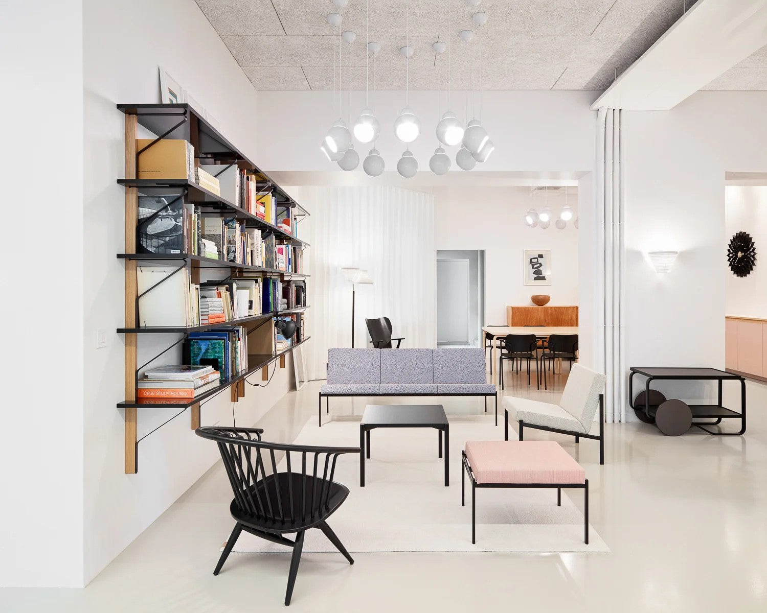 Modern office interior with bookshelf, chairs, and tables.
