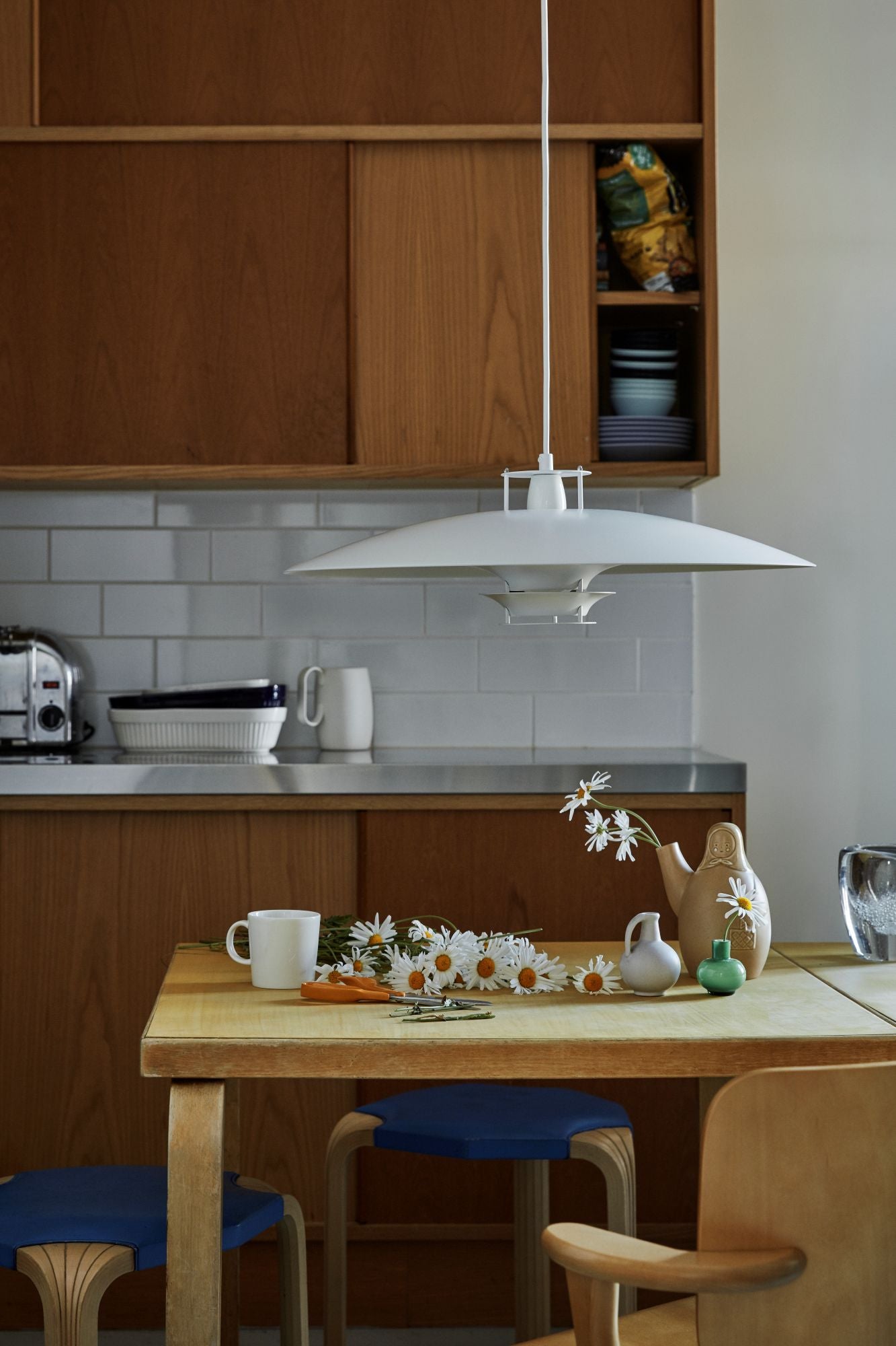 Kitchen with wooden table, chairs, and a white pendant light.