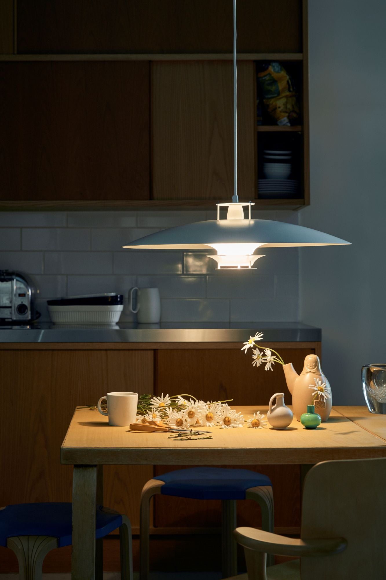 Modern kitchen with pendant light, dining table, and chairs.