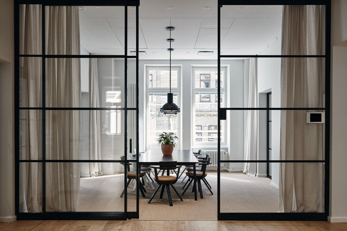 Modern interior with glass partition doors leading to a dining area.