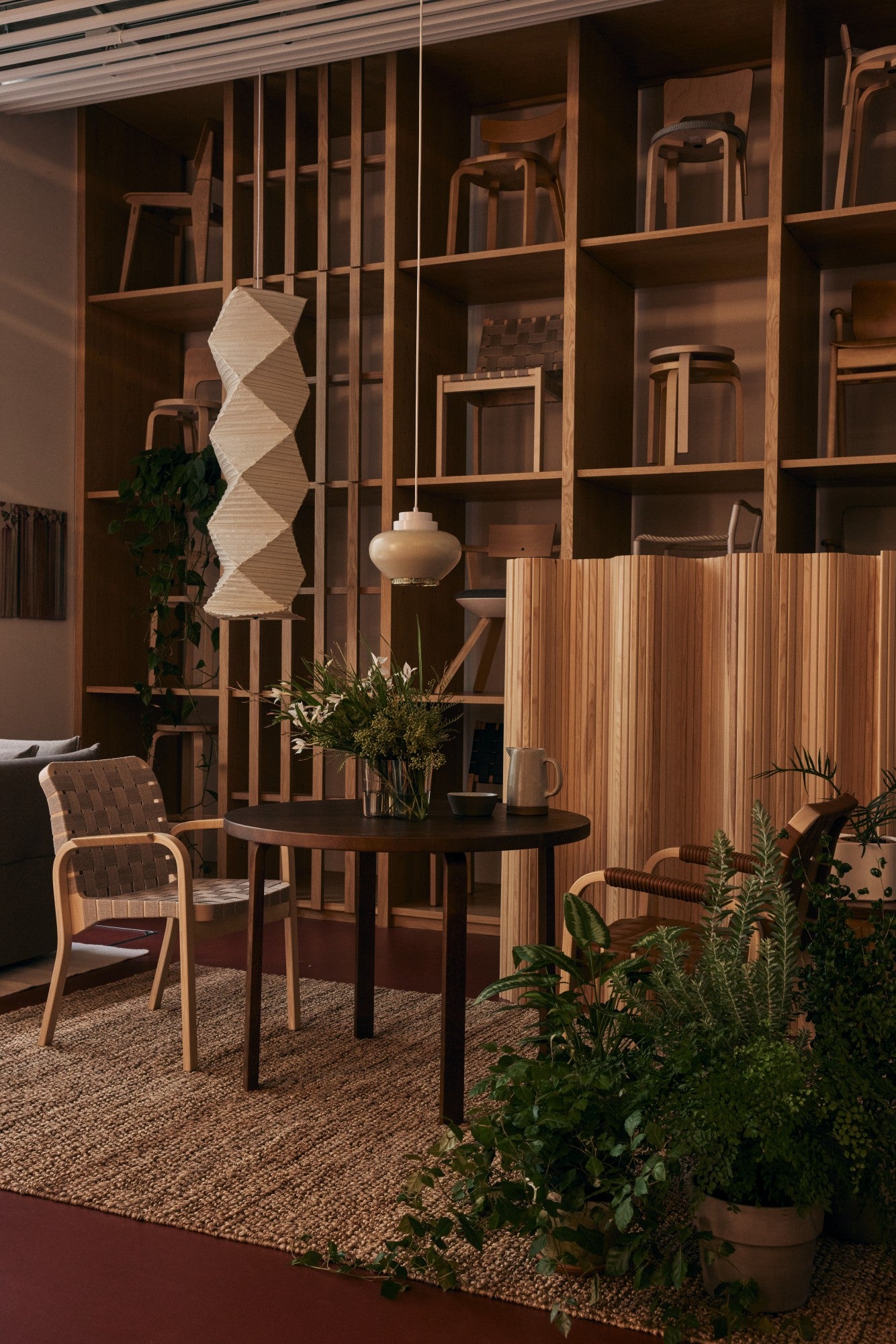 Modern interior design with wooden shelves, table, chairs, and plants.
