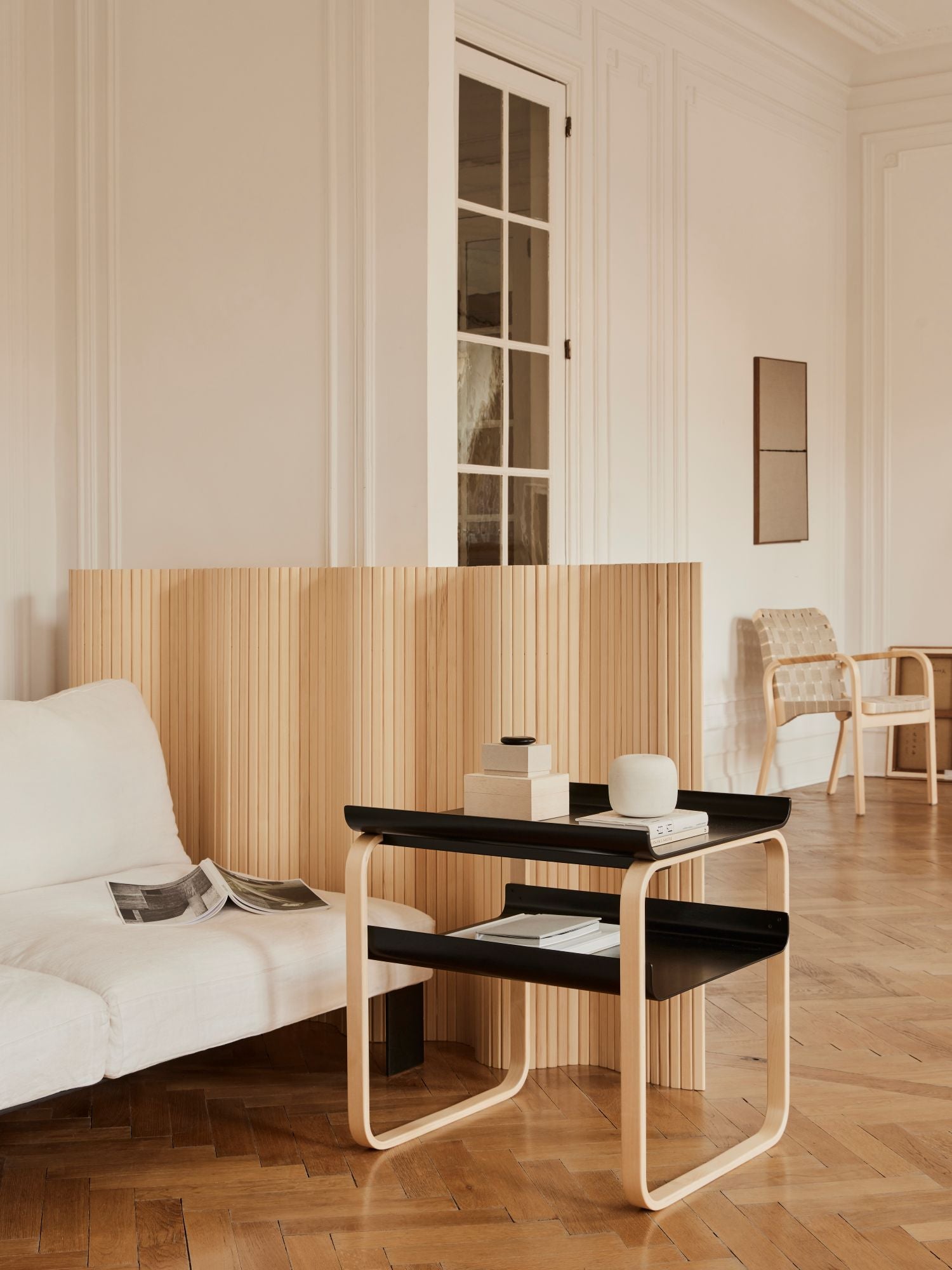 Modern living room with a black and white side table, white sofa, and wooden floor.