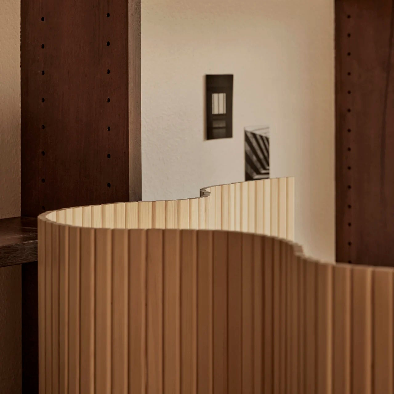 Shelving unit with books and a cylindrical wooden object in a minimalistic setting.