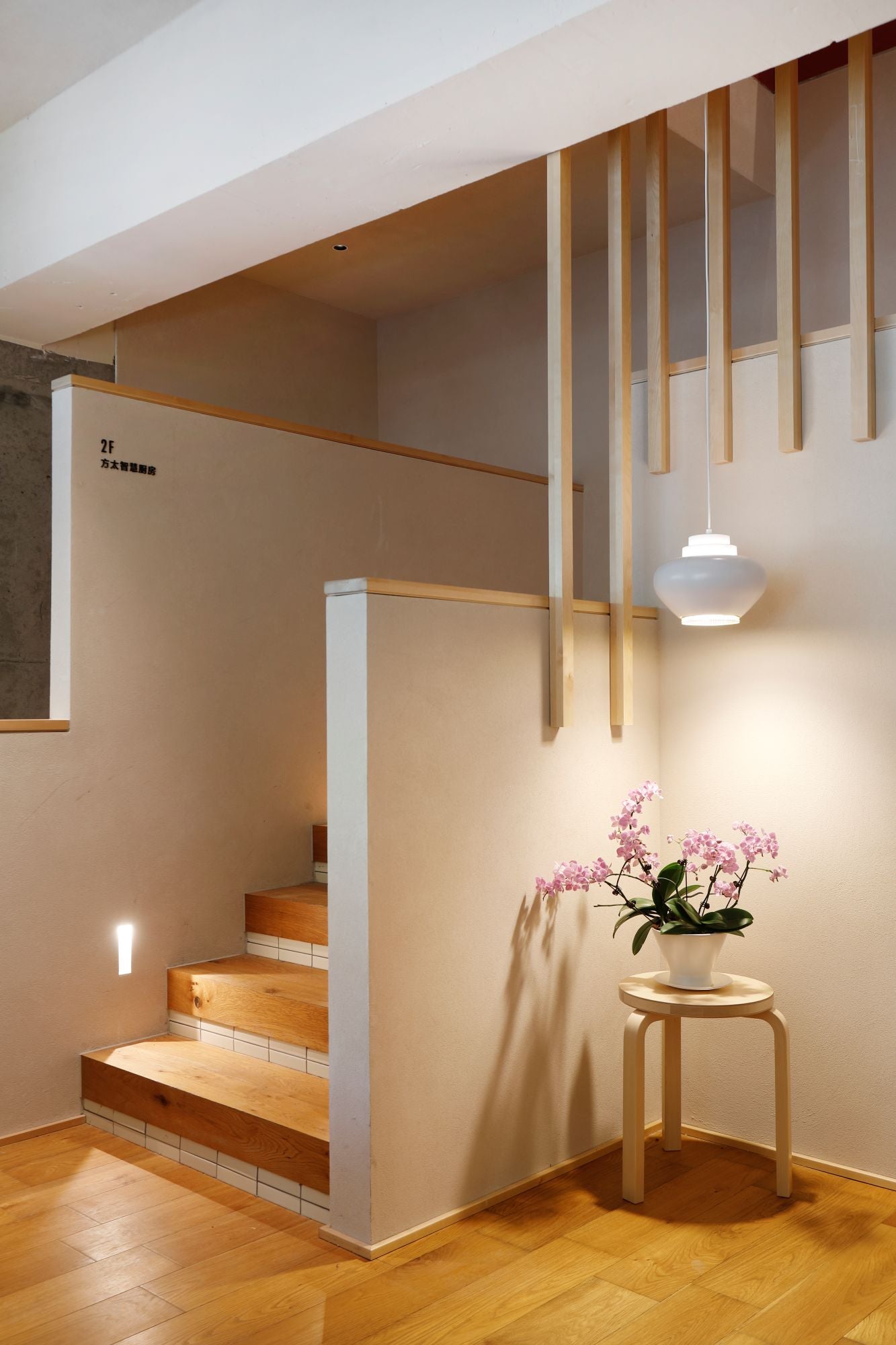 Modern interior with wooden staircase and decorative plant on a small table.