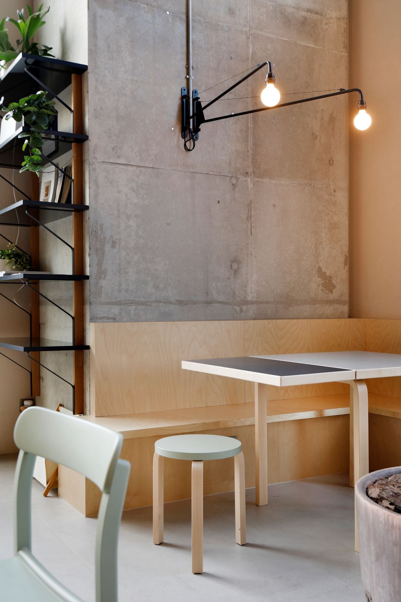 Modern interior with a table, chairs, and a light fixture against a concrete wall.