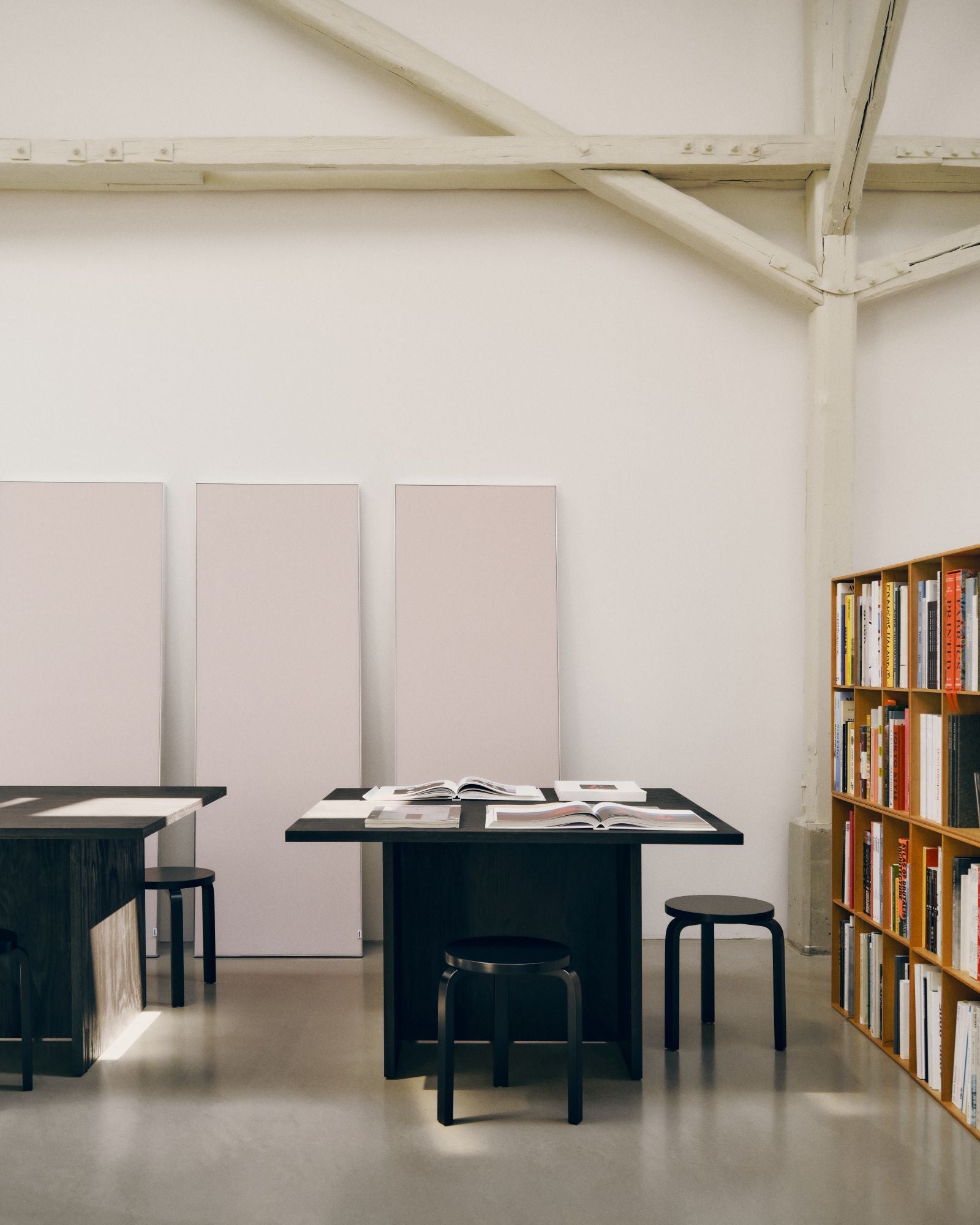 Modern interior with black dining table, chairs, and a bookshelf against a white wall.