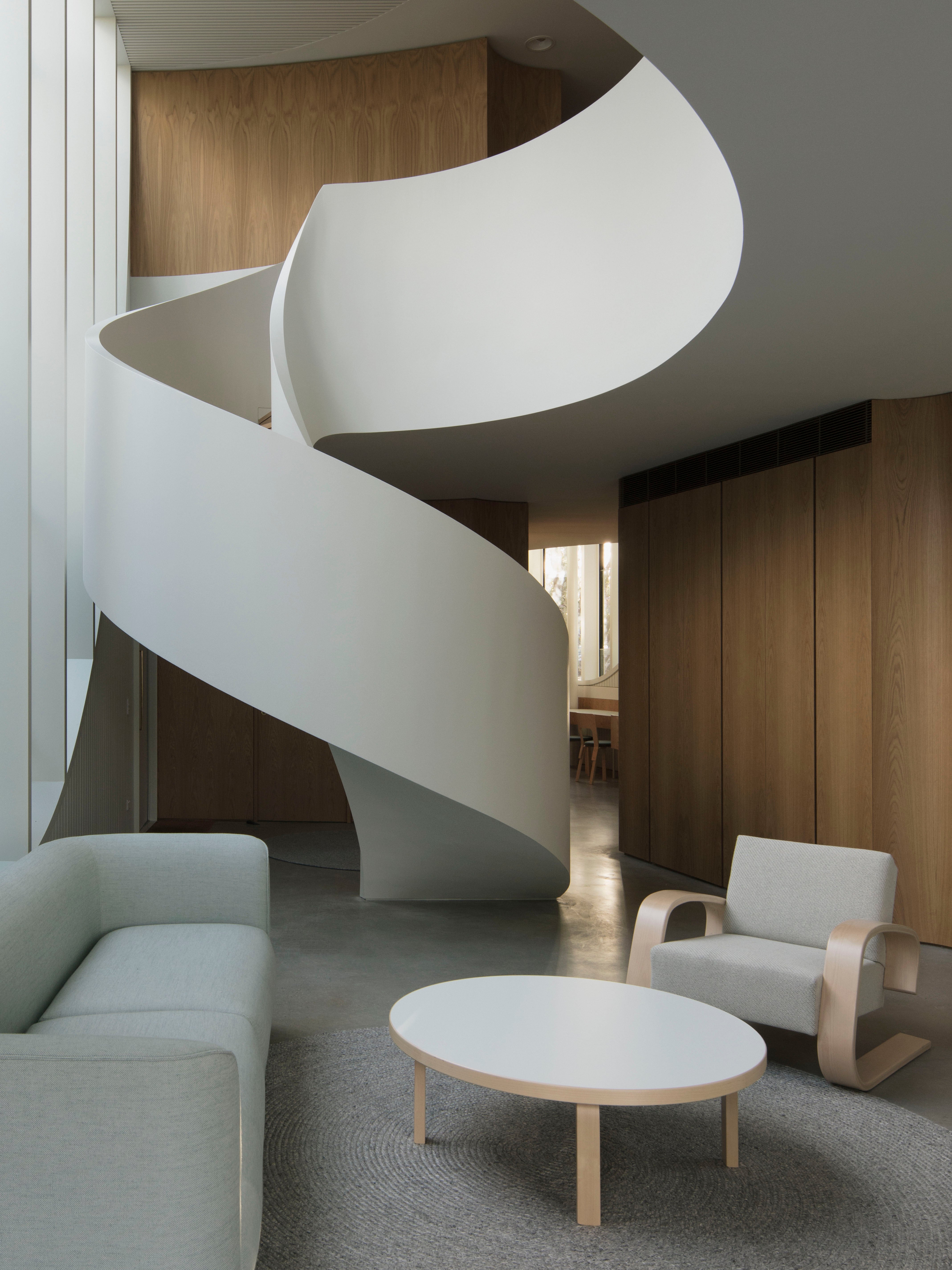 Modern interior with a spiral staircase, white sofa, and round coffee table.