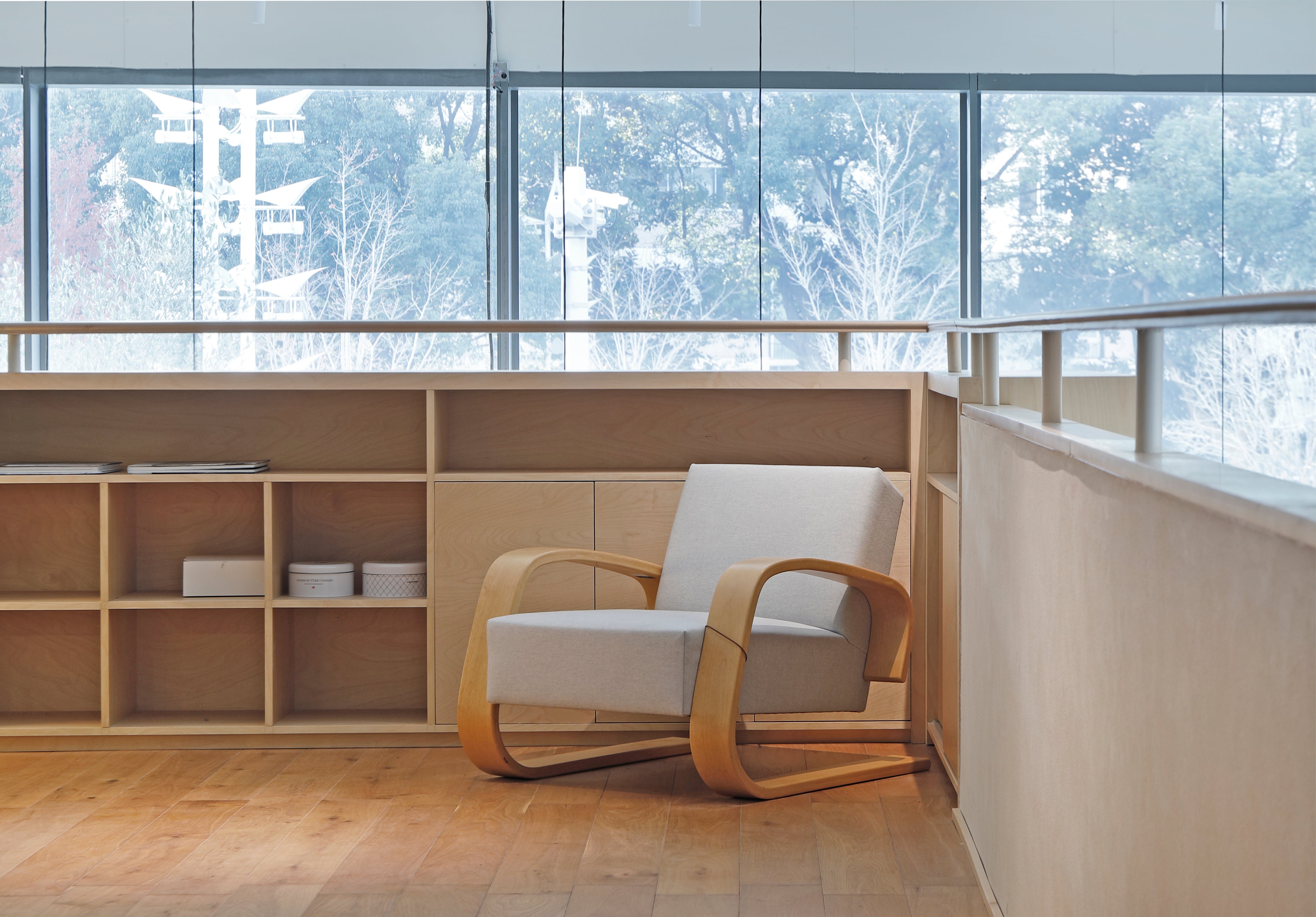 Modern chair in a room with large windows and wooden shelves.