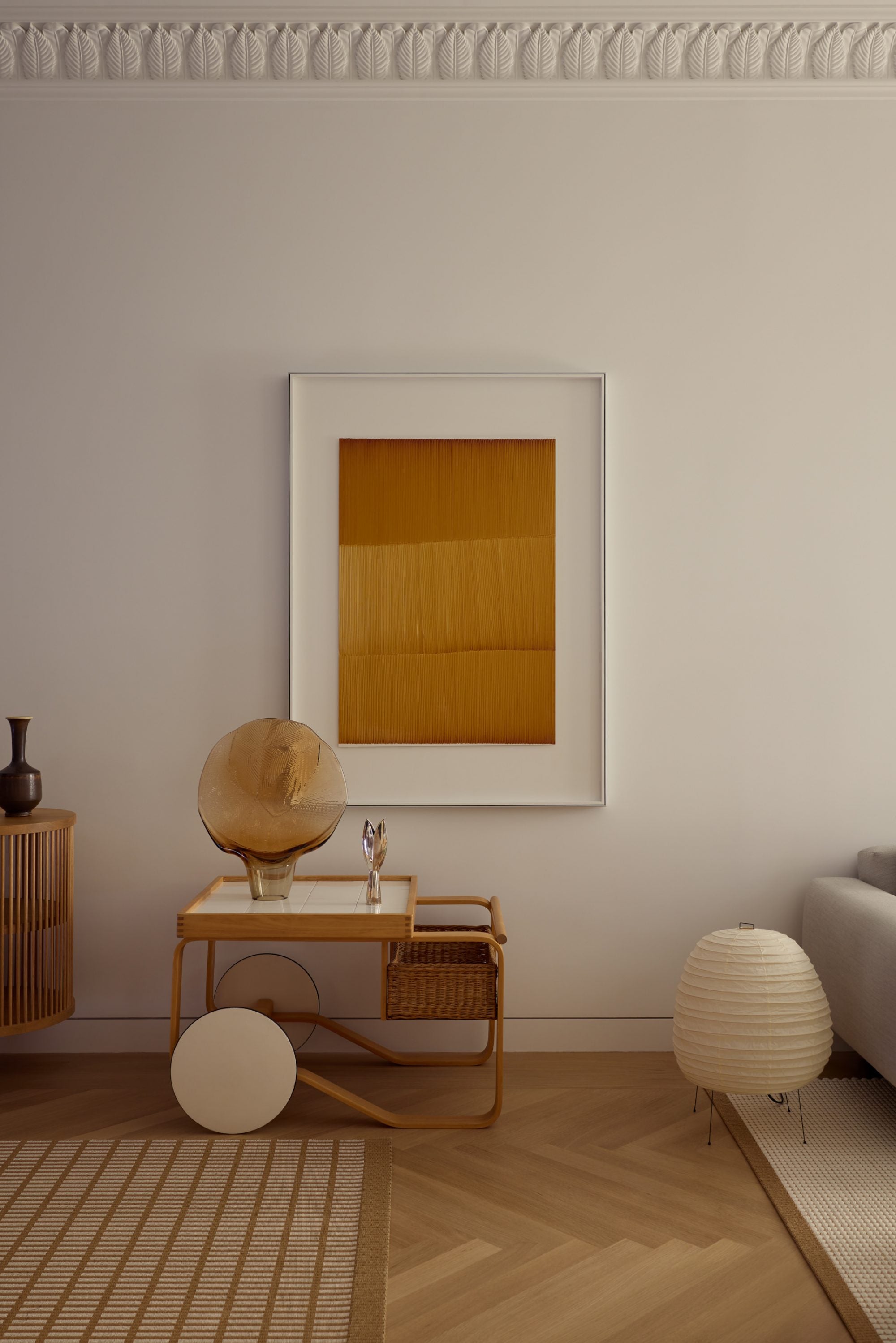 Modern interior with a framed abstract painting on a wall, side table with decorative items, and lamp.
