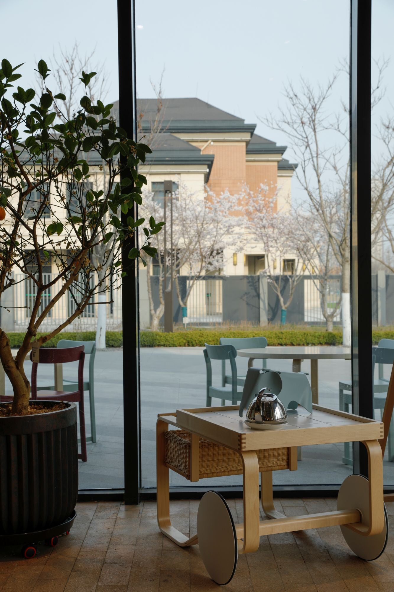 Modern cart with a teapot on a wooden floor, large glass door in the background