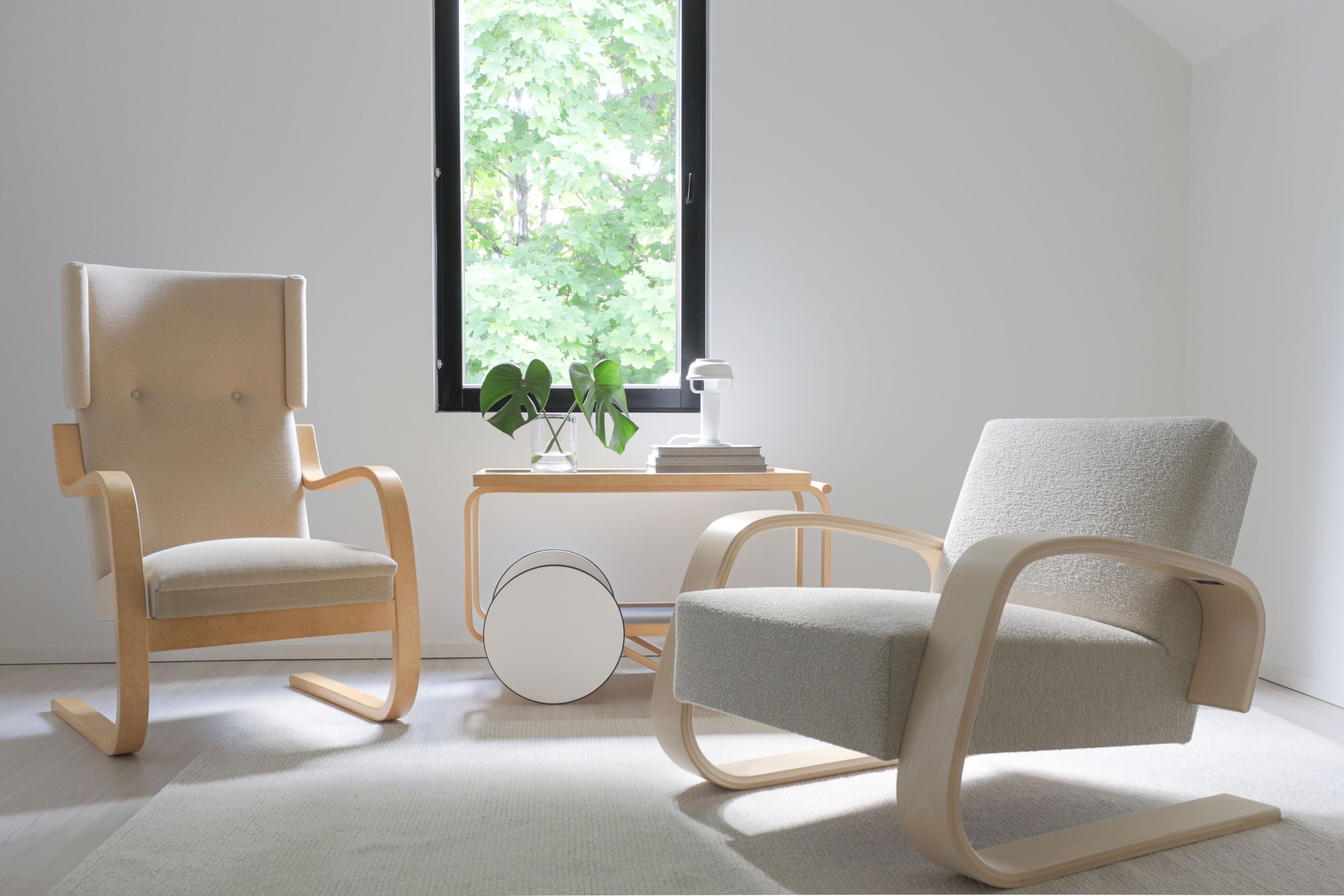 Two modern chairs in a minimalistic room with a window and small table.