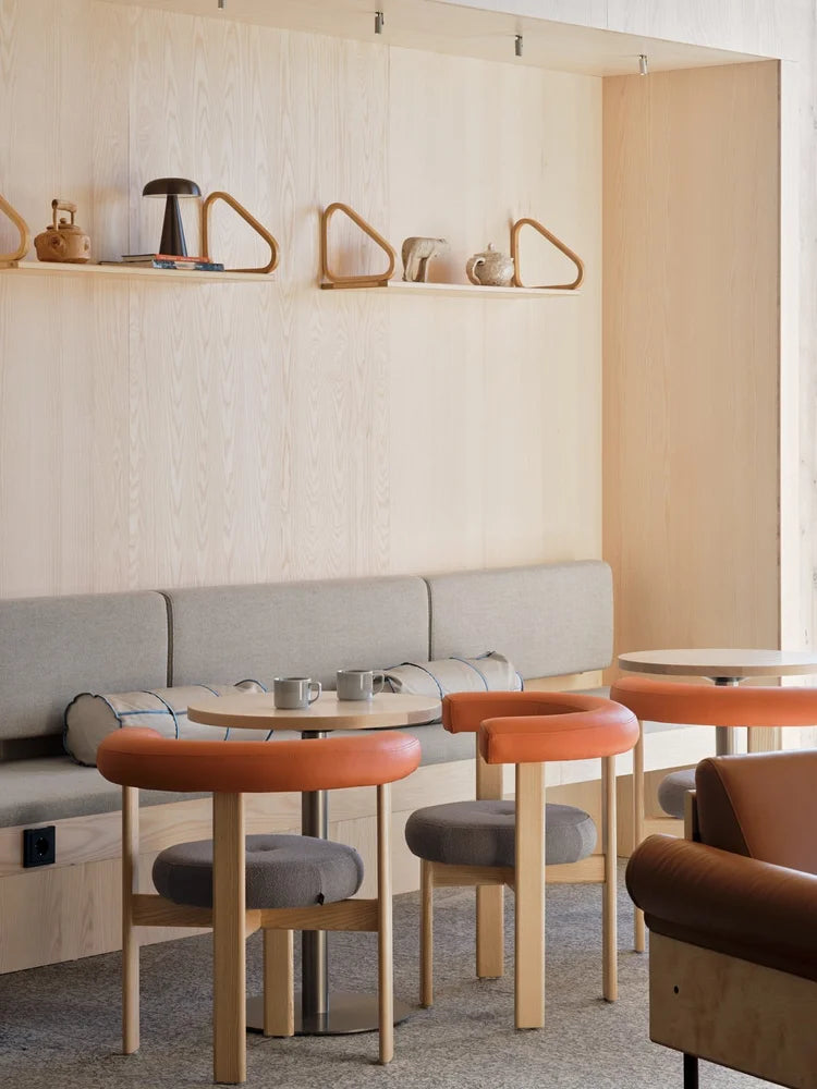 Modern interior with gray sofa, orange stools, and wooden tables.