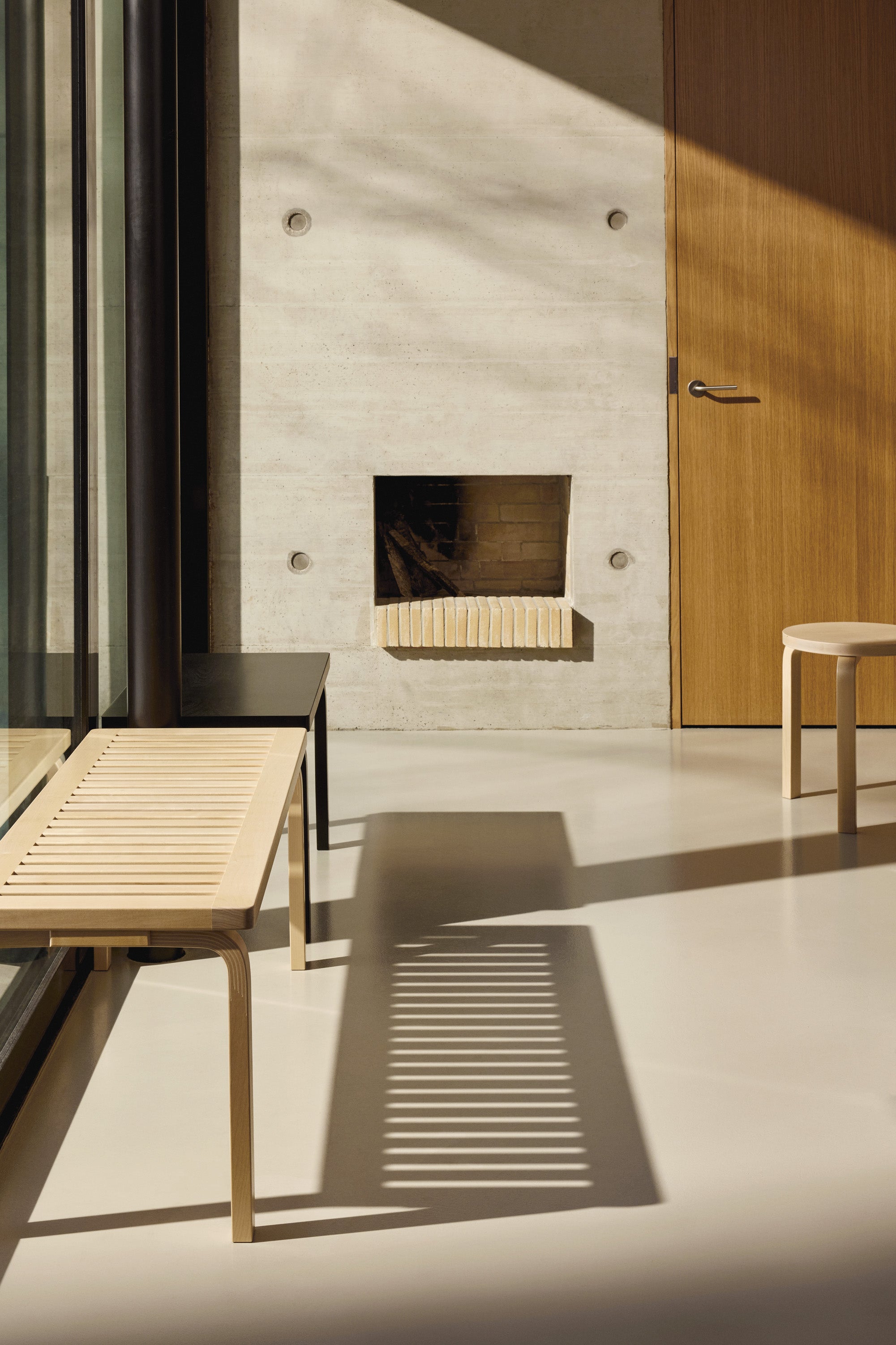 Modern interior with a concrete wall, wooden door, and minimal furniture.