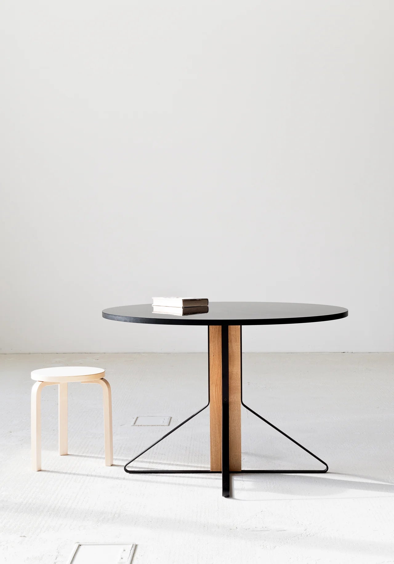Modern round dining table with a black top and wooden legs on a white background