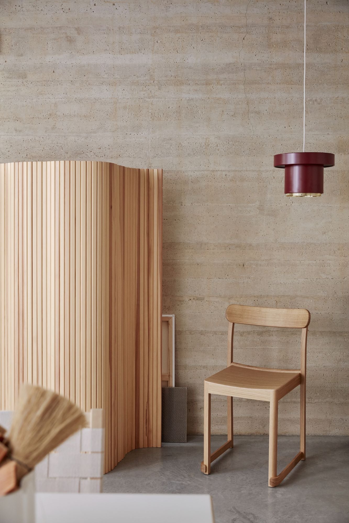 Wooden chair against a textured wall with a pendant light.