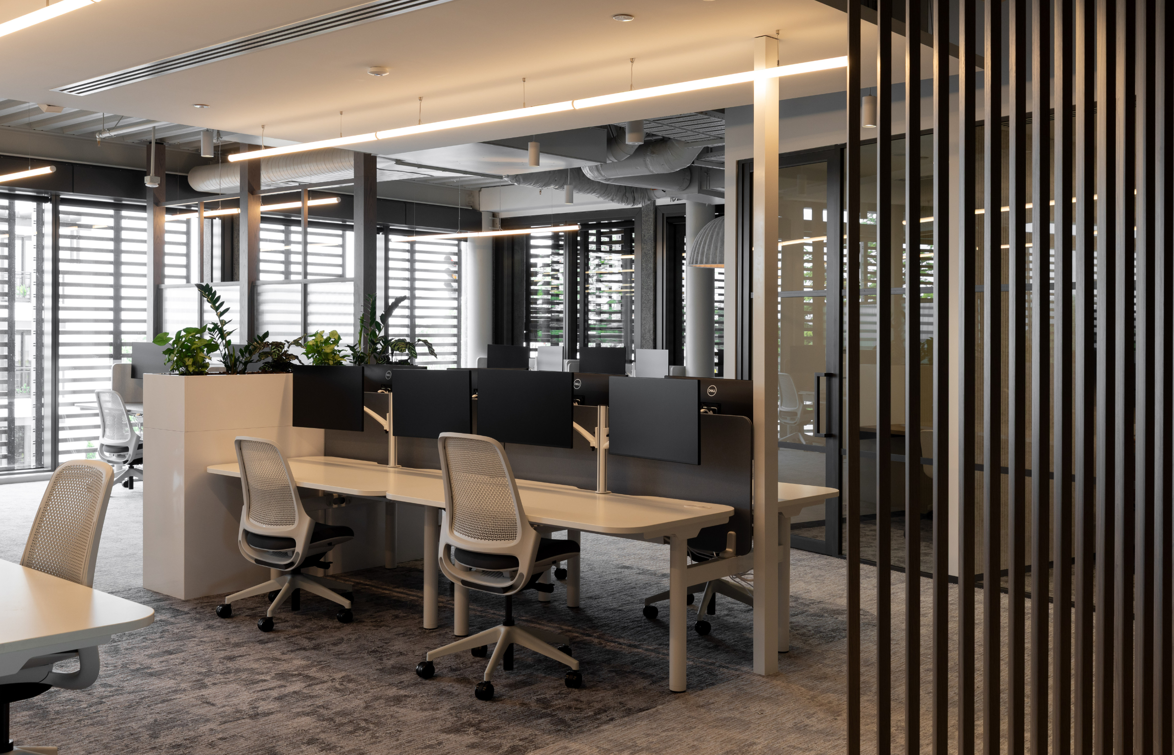 Modern office space with desks, chairs, and large windows.
